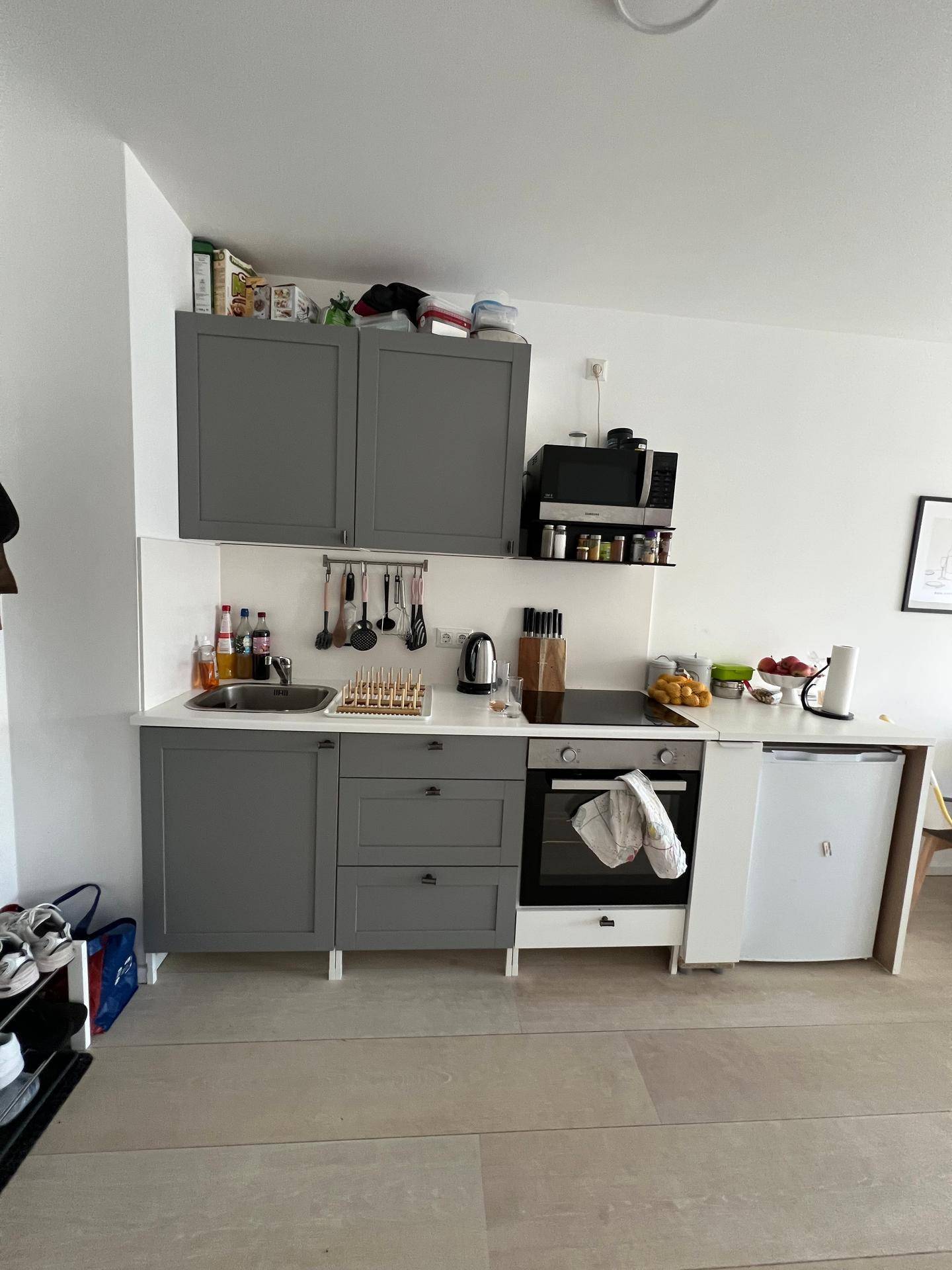 Detaillierte Ansicht der modernen Küchenzeile mit grauen Fronten, integriertem Ofen und Kühlschrank.