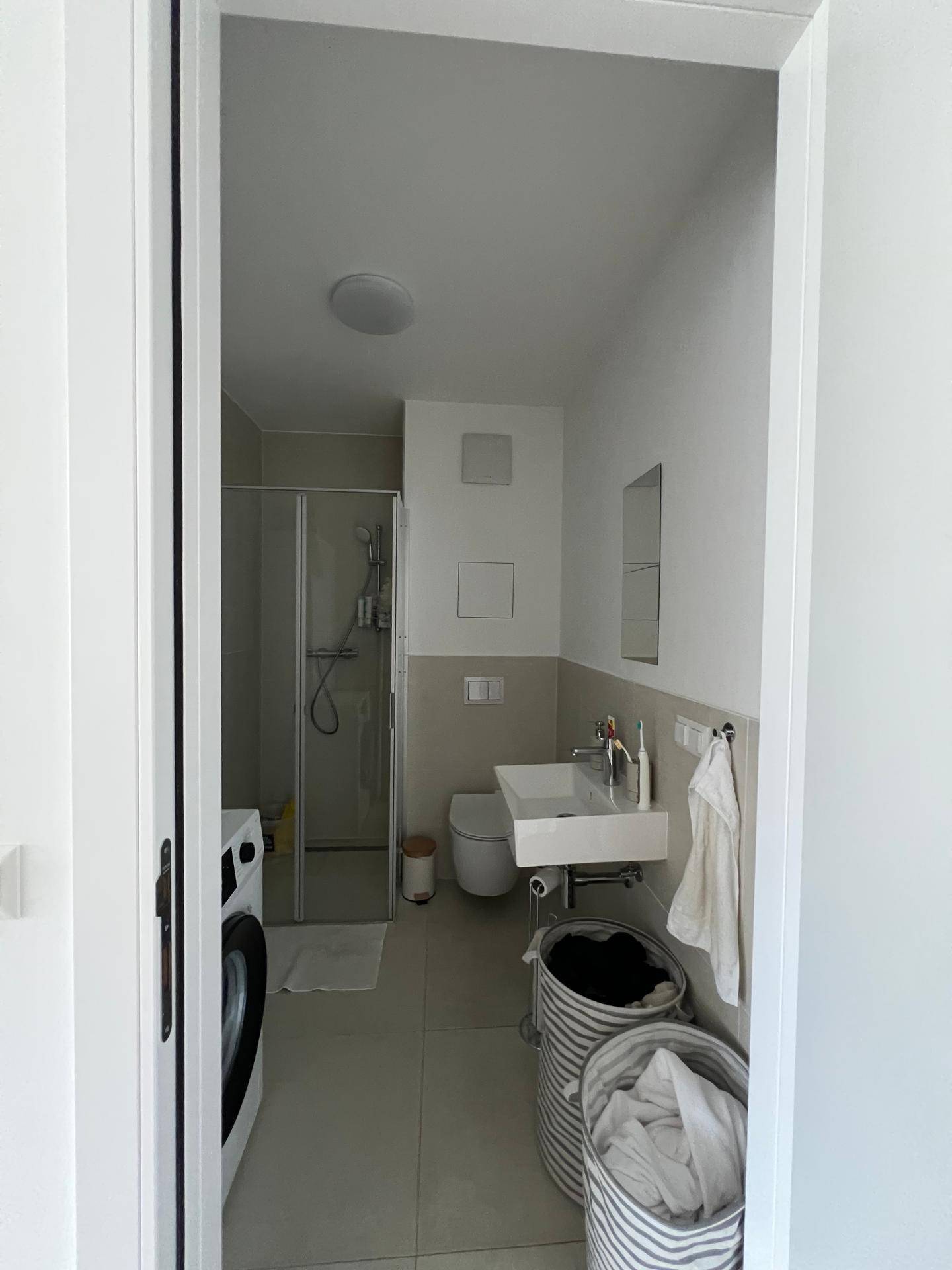 Modernes Badezimmer mit Duschkabine, Waschbecken, Toilette und Waschmaschine.