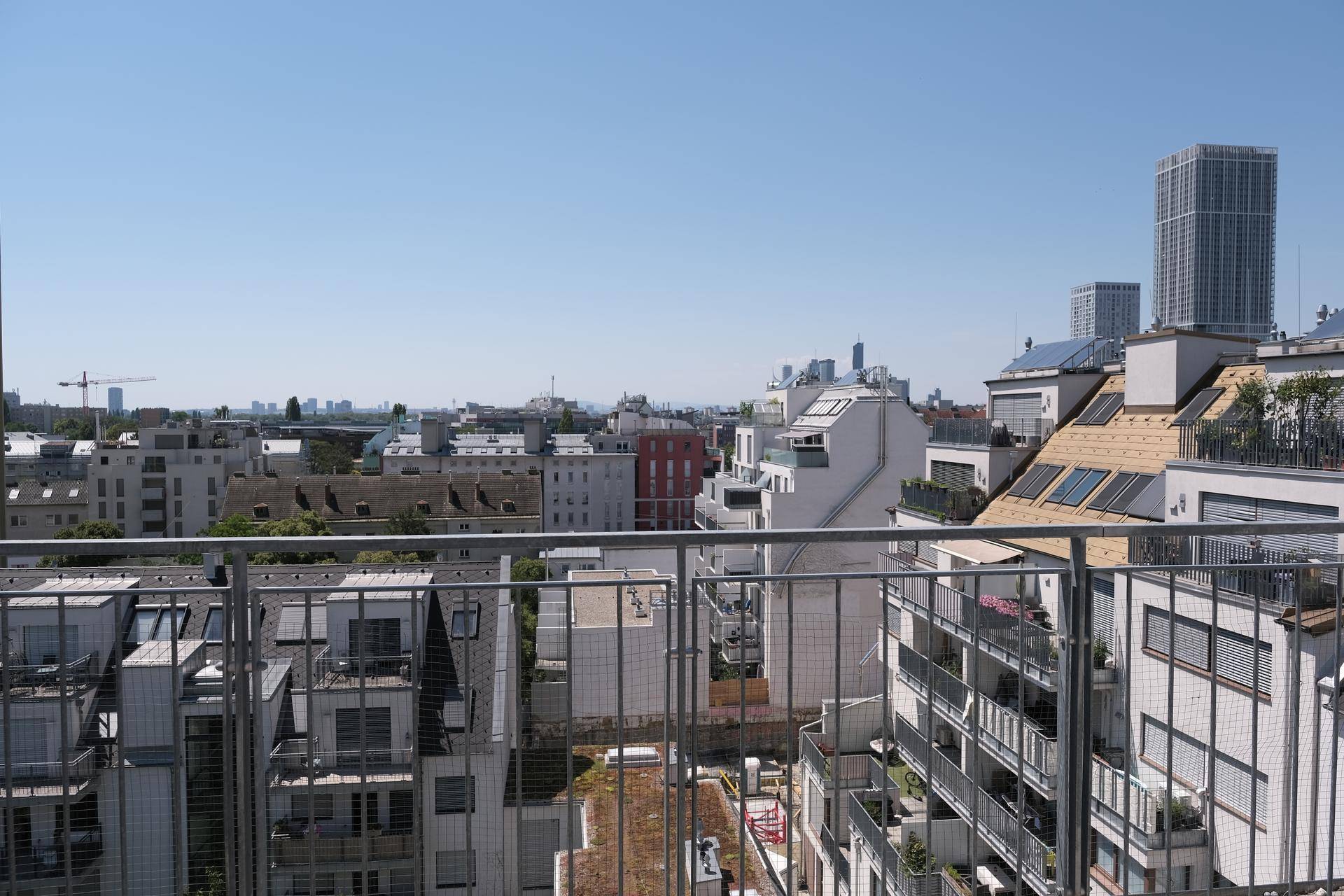 Weitläufiger Blick über die Stadt von einer Dachterrasse mit umliegenden Gebäuden.