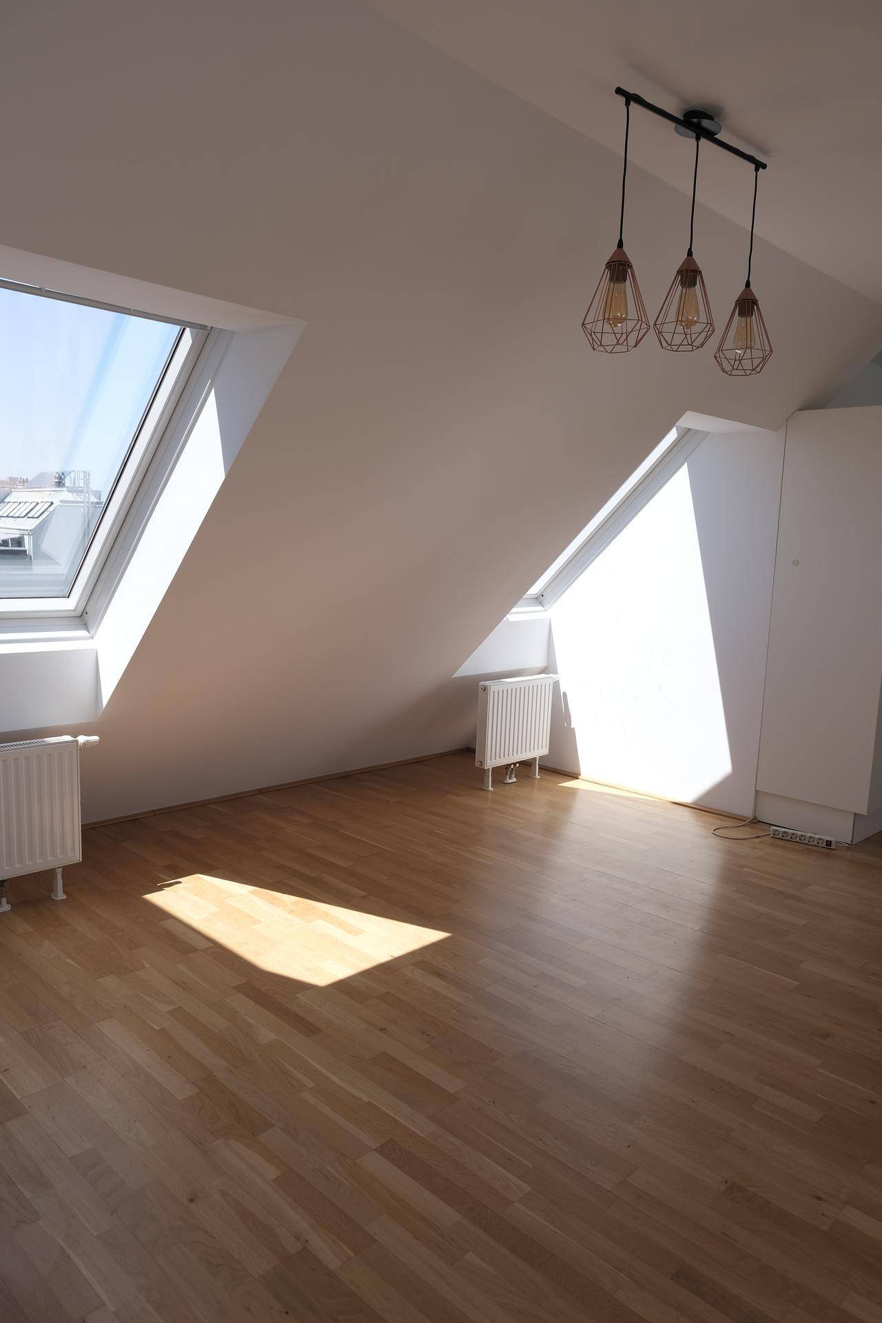 Lichtdurchfluteter Dachgeschossraum mit Holzboden, Dachfenstern und viel Tageslicht.