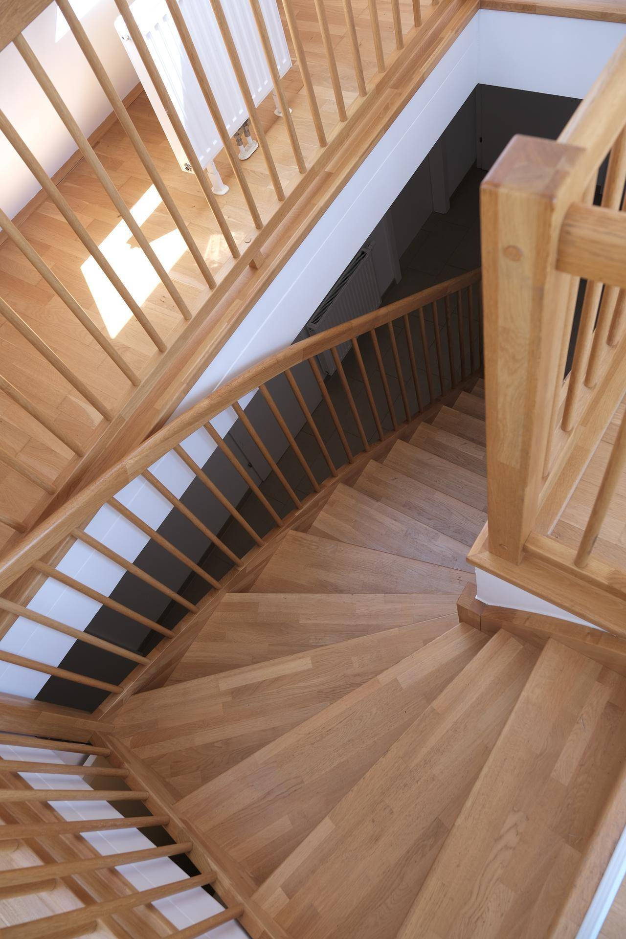 Elegante Holztreppe mit geschwungenem Geländer, die die verschiedenen Ebenen verbindet.