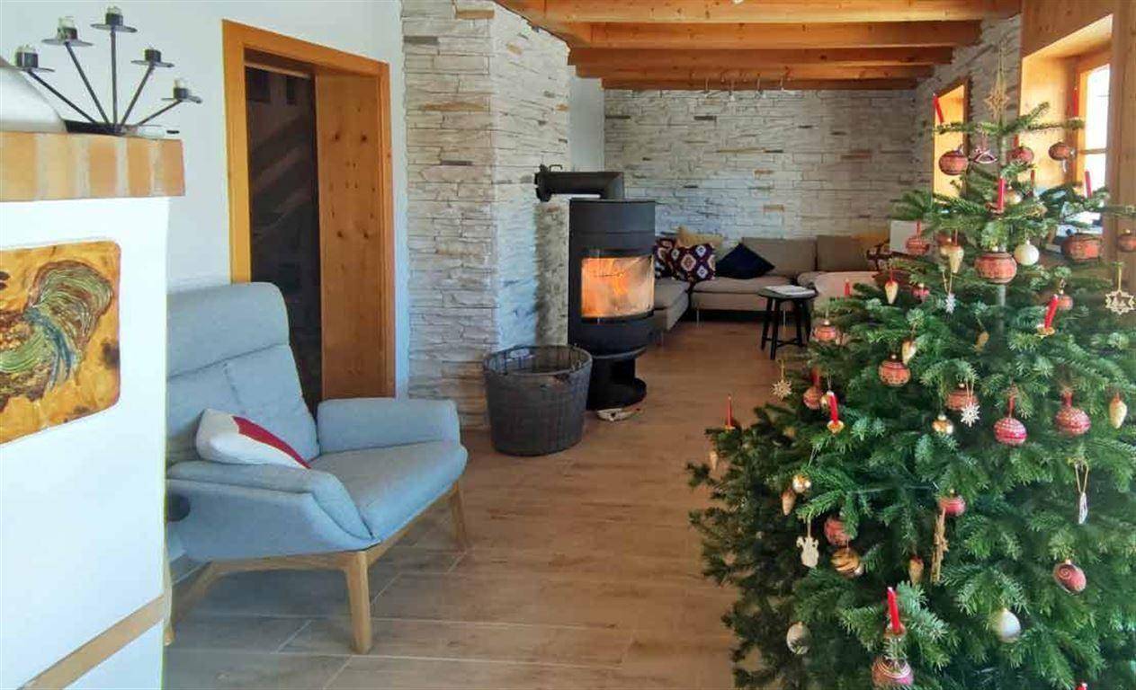 Helles Wohnzimmer mit Holzofen und festlichem Weihnachtsbaum, bietet eine warme und einladende Atmosphäre.