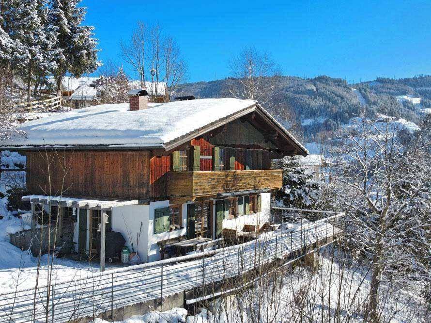 Charmantes Chalet in winterlicher Bergkulisse mit schneebedecktem Dach und traditionellen Fensterläden.