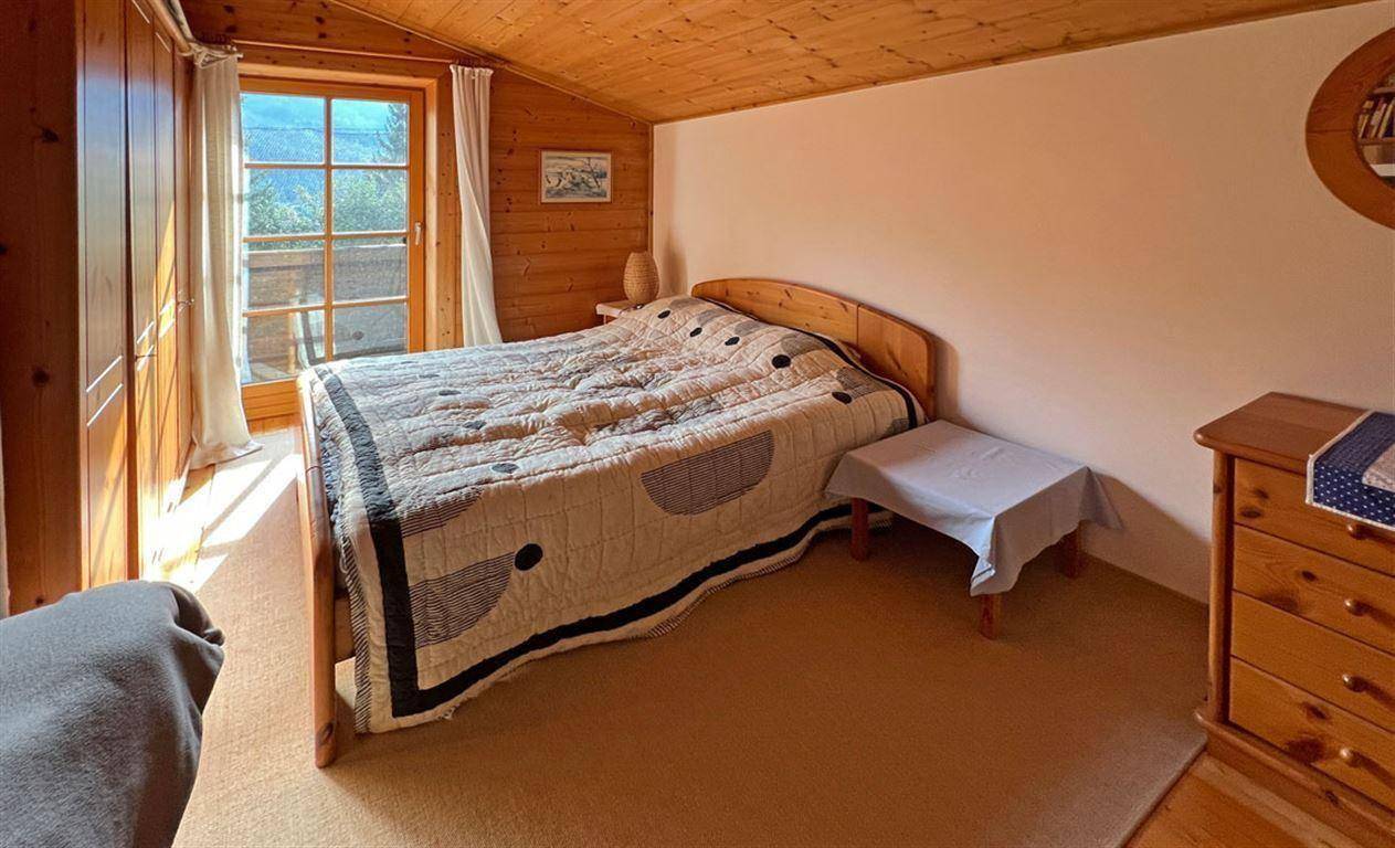 Helles Schlafzimmer mit Holzwänden, Doppelbett und direktem Zugang zu einem Balkon.
