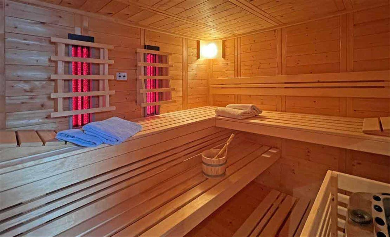 Holzvertäfelte Sauna mit Infrarotstrahlern und traditionellen Saunabänken für Entspannung.