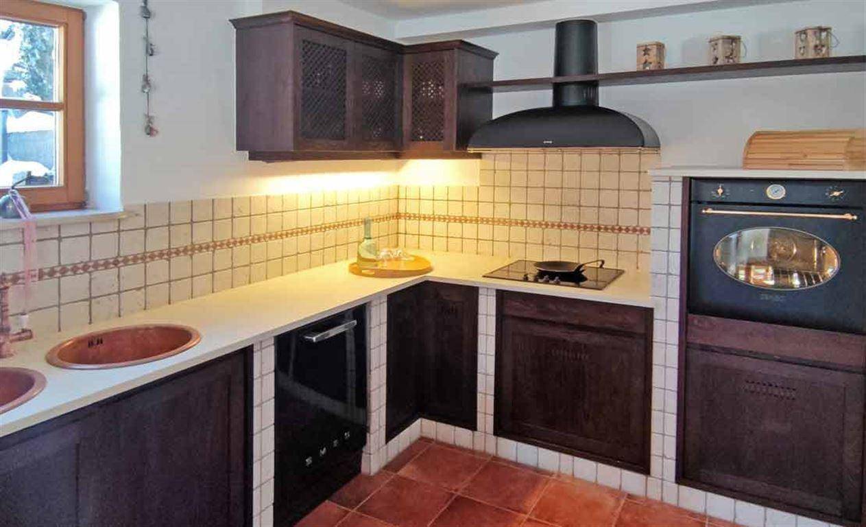 Traditionelle Küche mit dunklen Holzschränken, Fliesenrückwand und zwei Kupferspülbecken.
