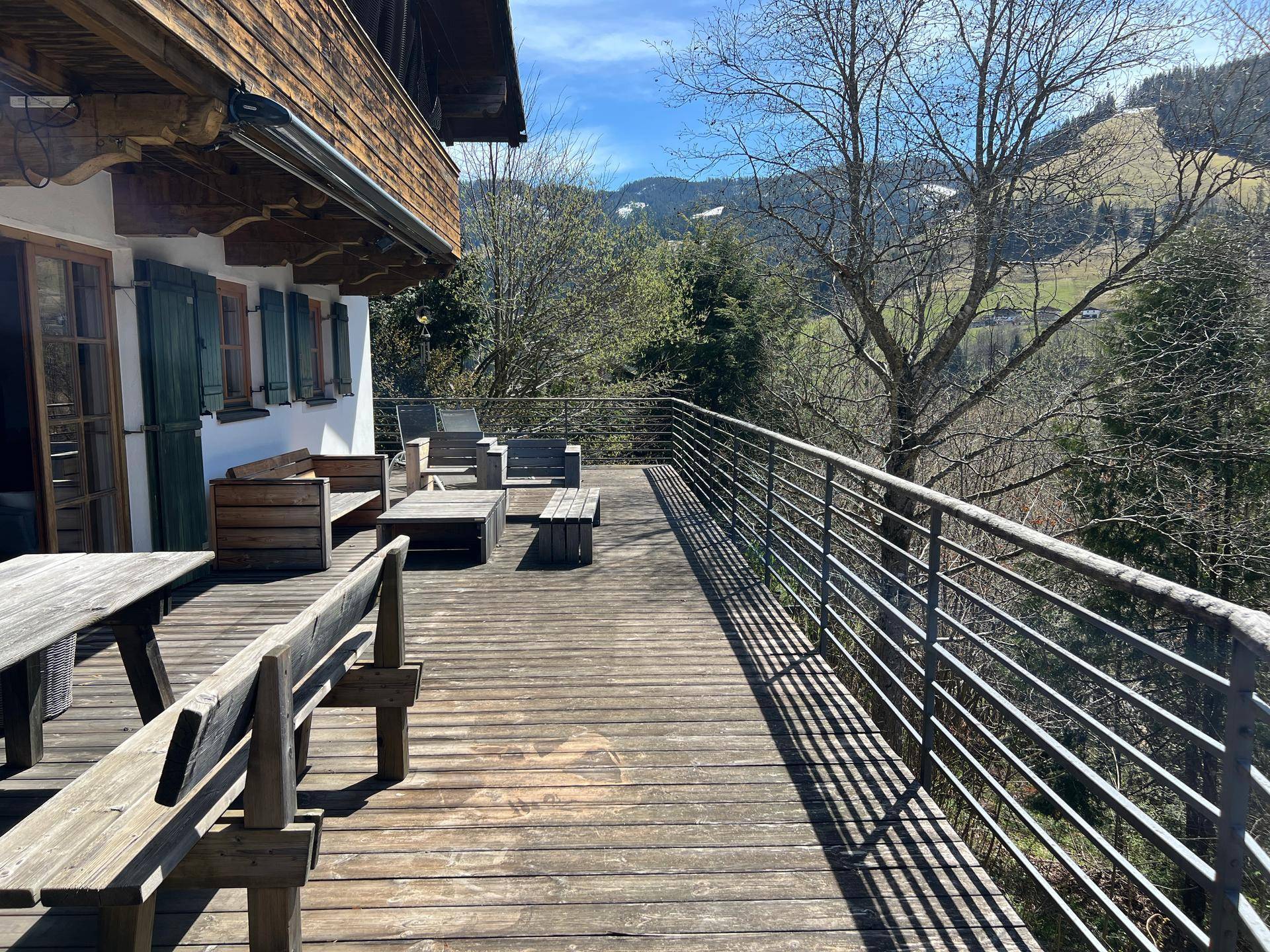Große Holzterrasse mit verschiedenen Sitzgelegenheiten und weitem Blick auf die umliegende Berglandschaft.