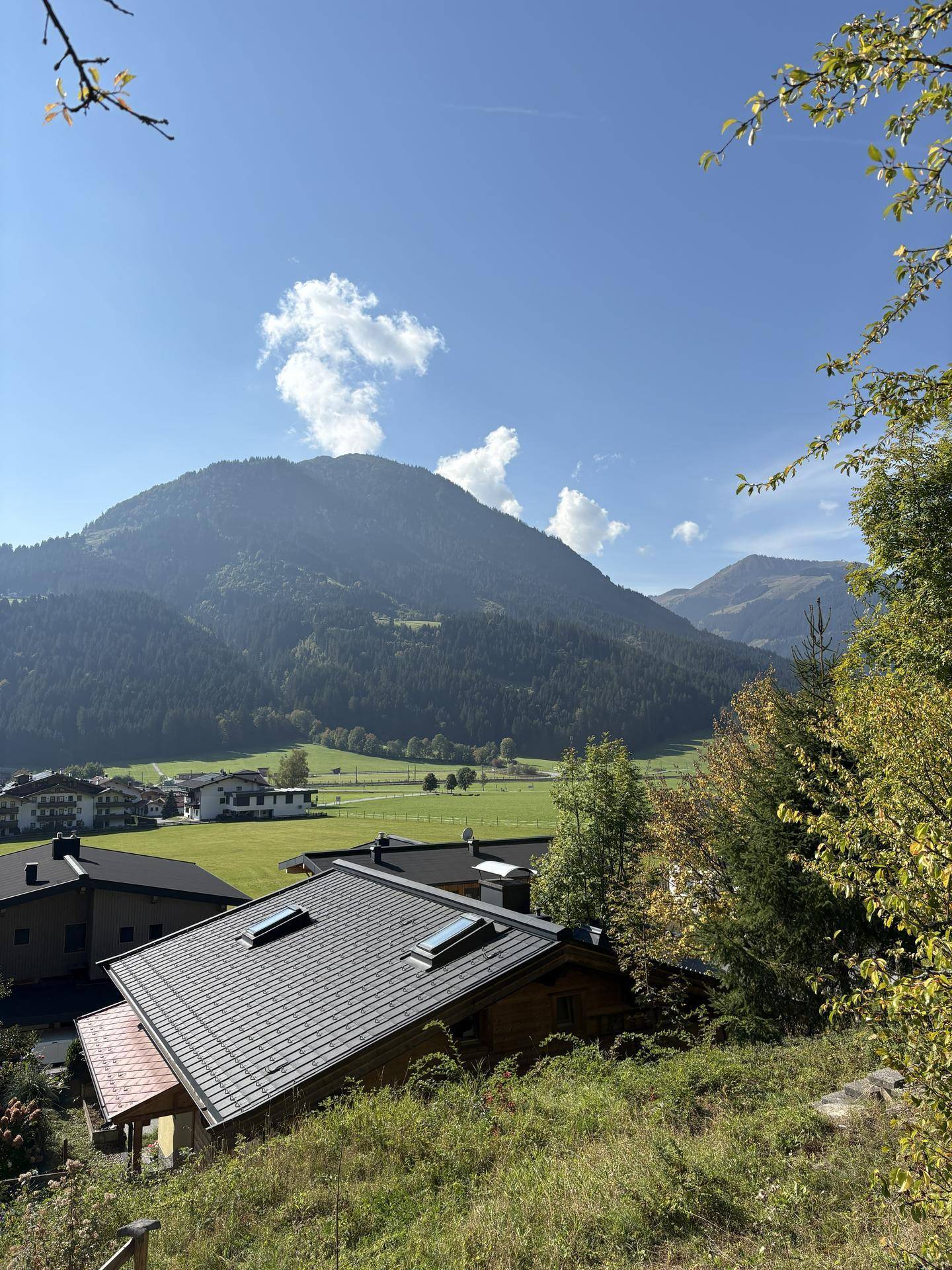 Blick auf ein Dorf mit traditionellen Dächern und Dachfenstern, umgeben von majestätischen Bergen.
