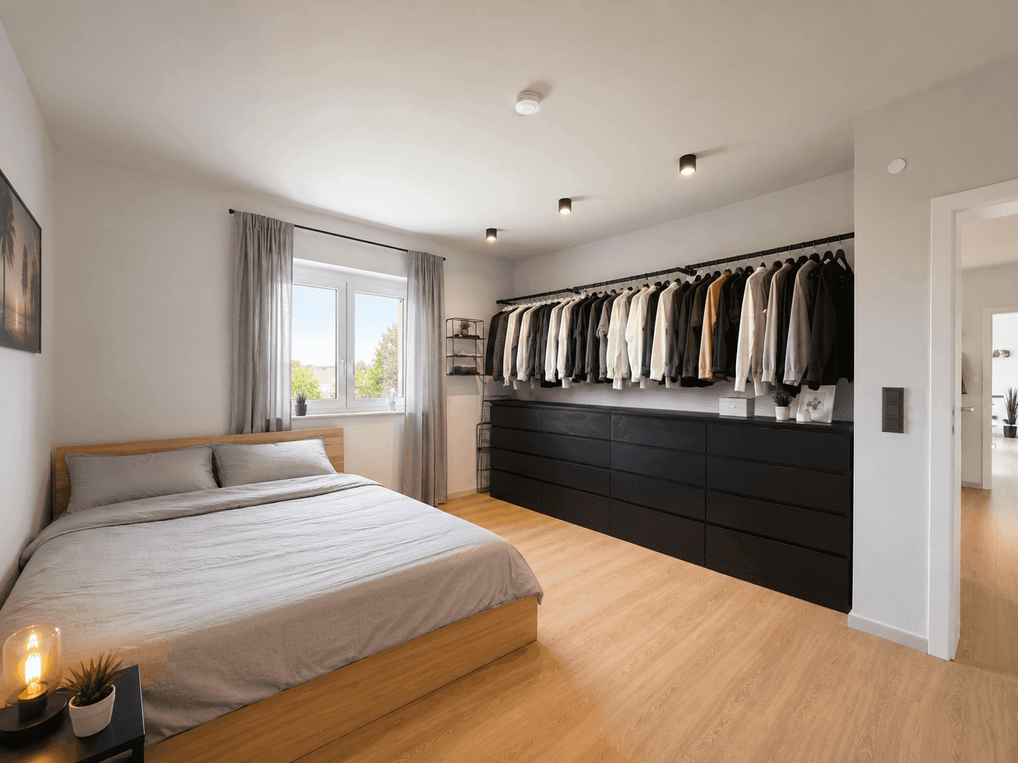 Schlafzimmer mit Doppelbett, offenem Kleiderschrank und Laminatboden, hell und funktional.