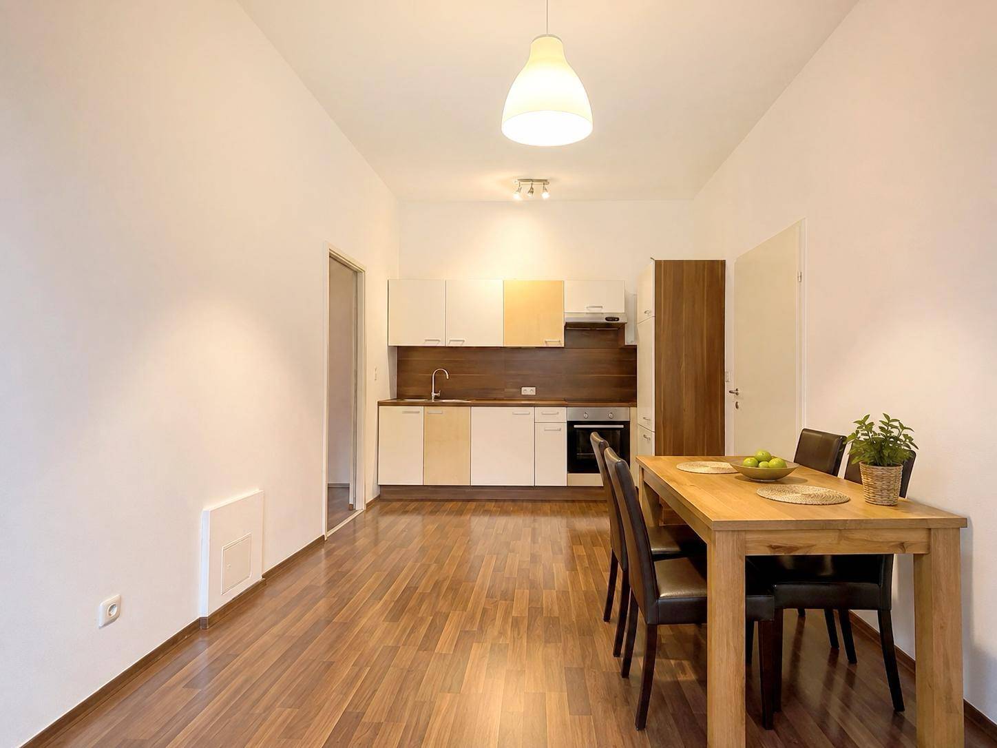 Moderne Einbauküche mit Essbereich, Holzboden und hellen Schränken in offener Gestaltung.