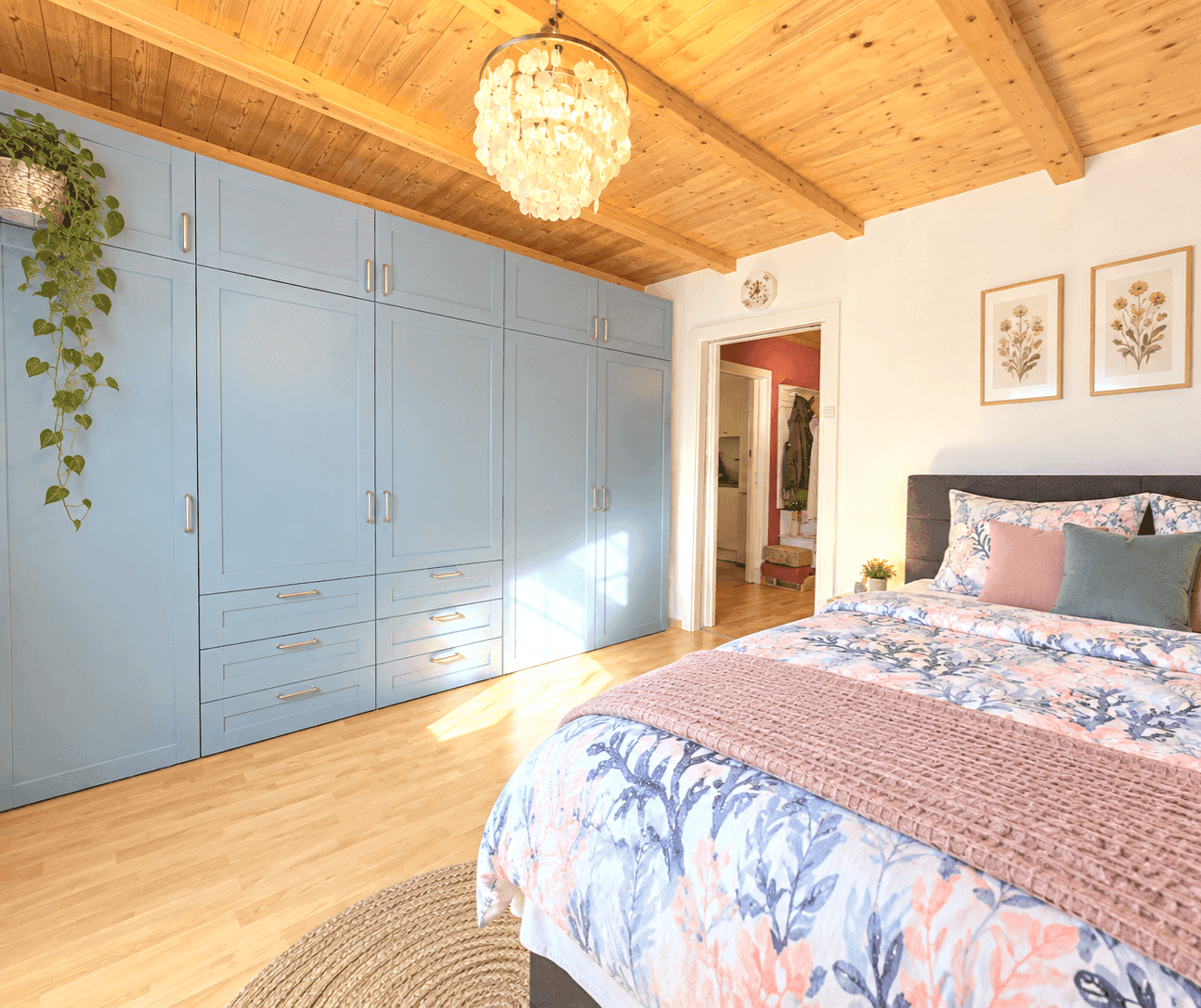 Geräumiges Schlafzimmer mit blauen Einbauschränken und heller Holzbalkendecke.