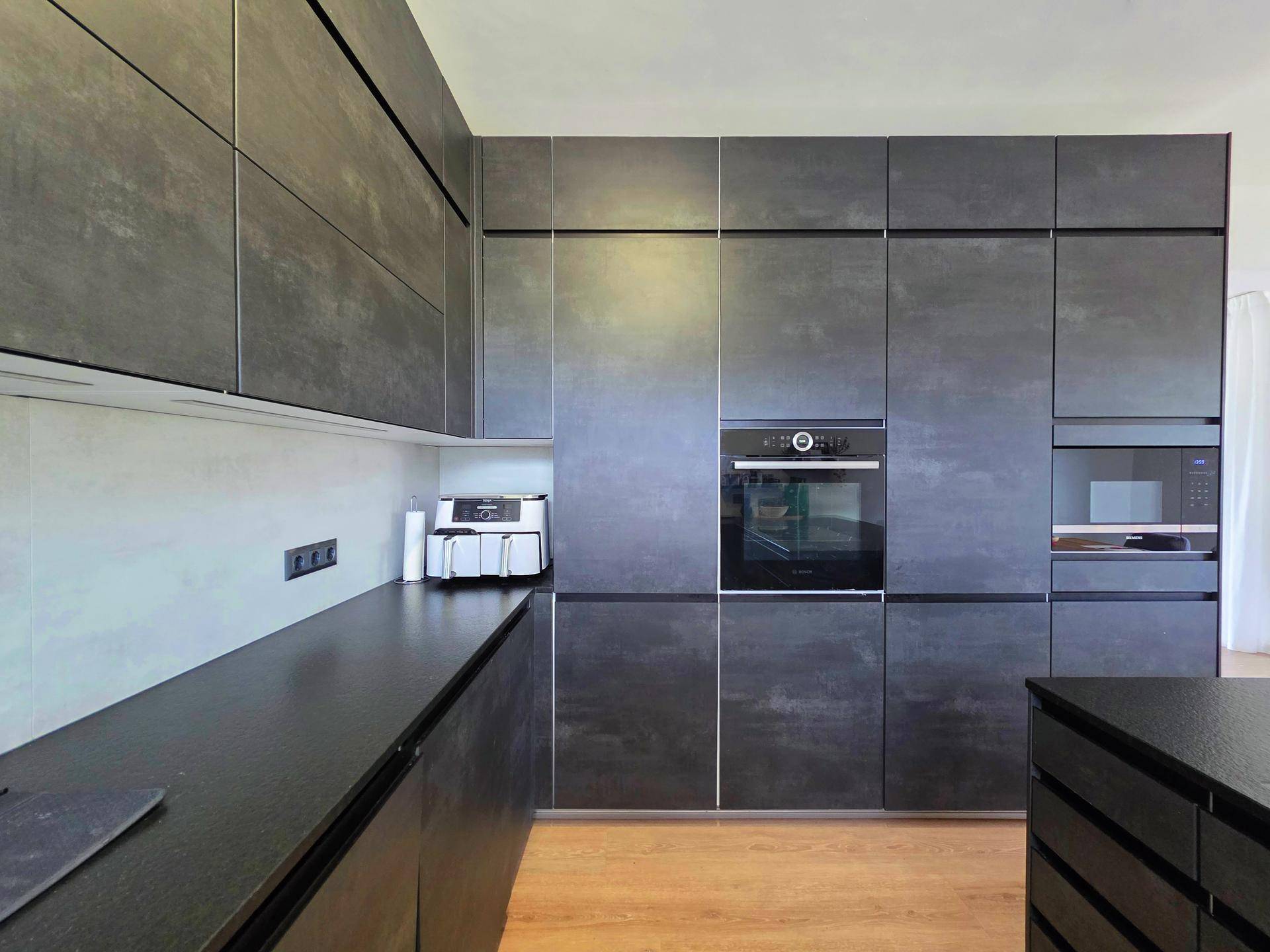 Stilvolle Einbauküche mit dunklen Fronten, integriertem Backofen und viel Stauraum.