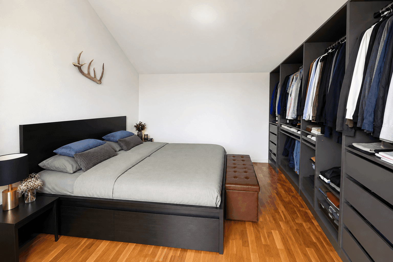 Schlafzimmer mit Doppelbett, Holzboden und integriertem, offenem Kleiderschranksystem.