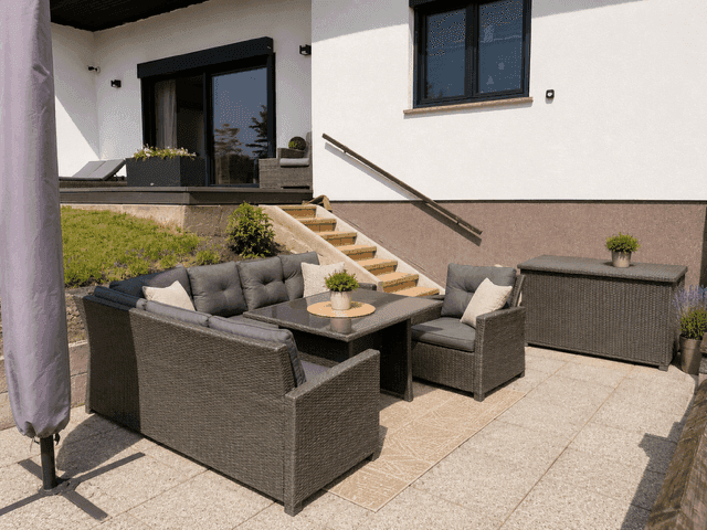 Gemütliche Steinterrasse mit bequemen Loungemöbeln und Treppenzugang zum Garten.