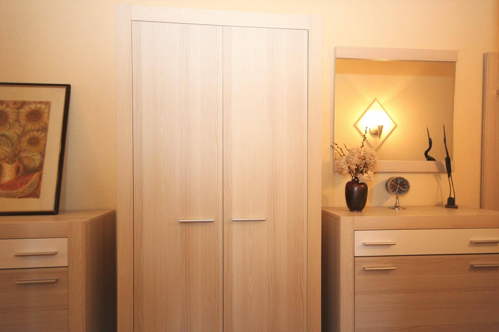 Heller Kleiderschrank und Kommode mit Spiegel in einem Schlafzimmer.