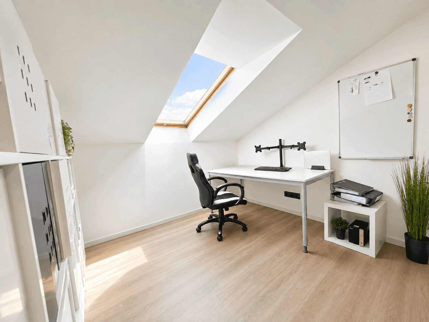 Helles Arbeitszimmer im Dachgeschoss mit Schreibtisch und großem Dachfenster.