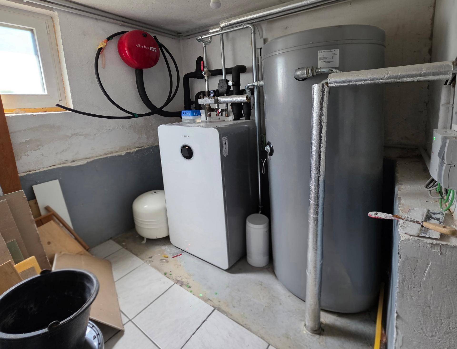 Technikraum im Kellergeschoss mit moderner Wärmepumpe und Warmwasserspeicher.
