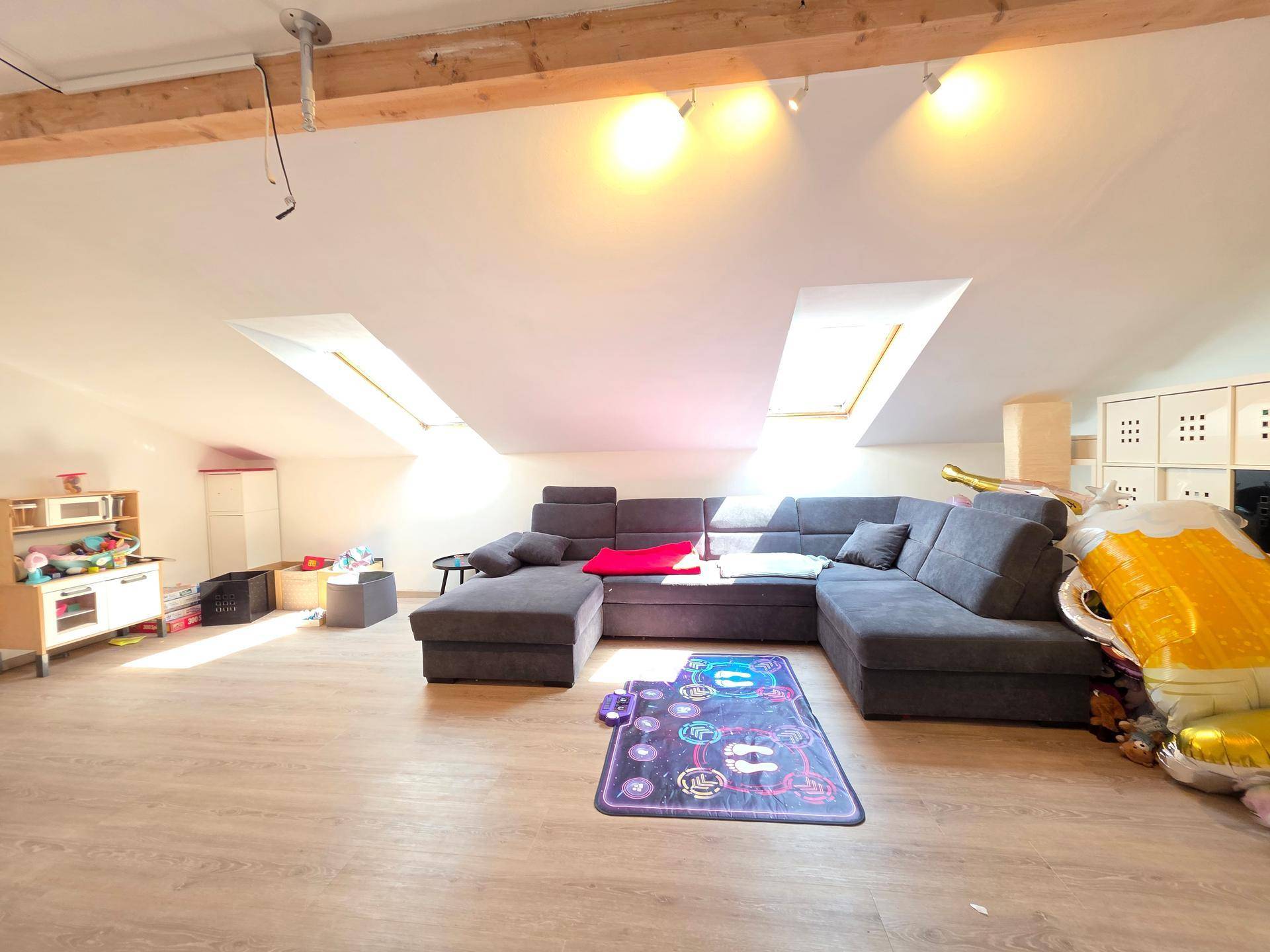 Geräumiges Wohnzimmer im Dachgeschoss mit gemütlicher Sitzecke und Dachfenstern.