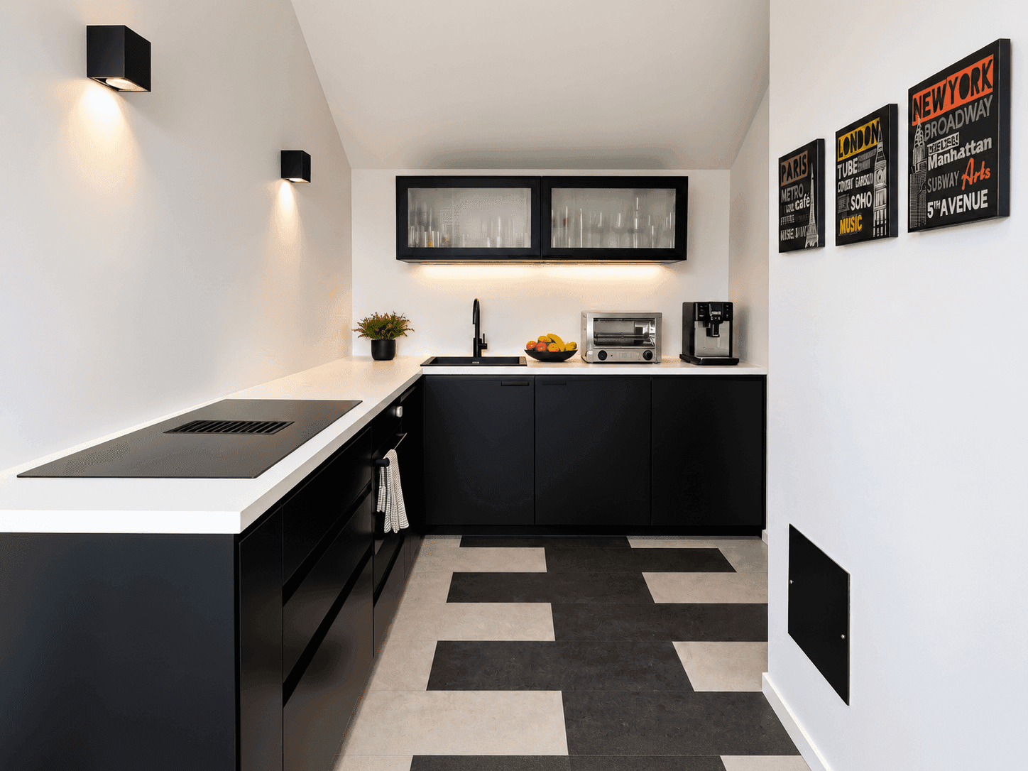 Moderne Küche mit schwarzen Schränken, weißer Arbeitsplatte und Induktionskochfeld.