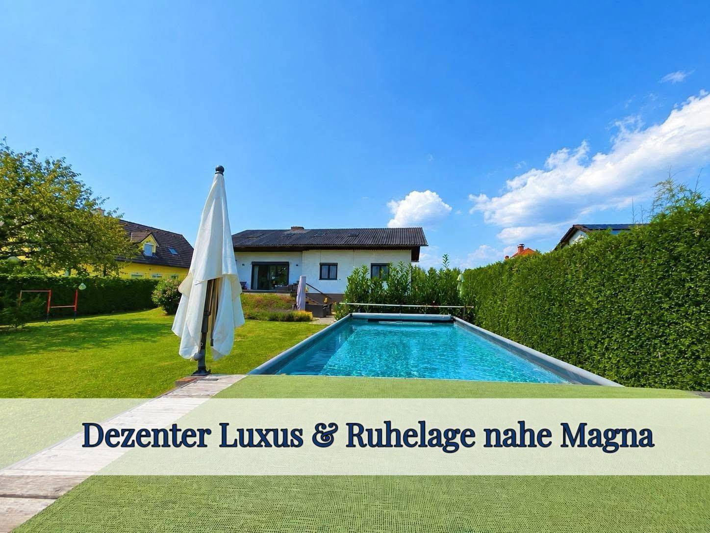 Großzügiger Gartenbereich mit privatem Pool und viel Grünfläche unter blauem Himmel.