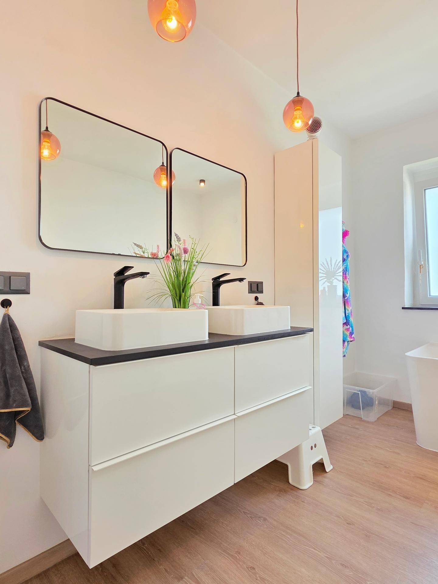 Modernes Badezimmer mit Doppelwaschbecken, zwei Spiegeln und stilvollen Pendelleuchten.