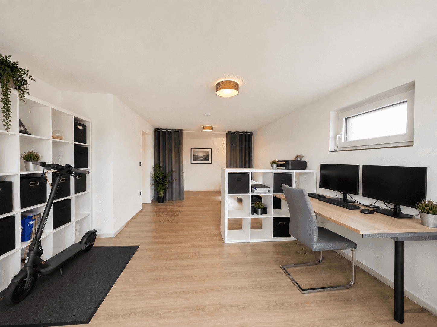 Geräumiger Büro- und Hobbybereich im Kellergeschoss mit Arbeitsplätzen und Regalen.