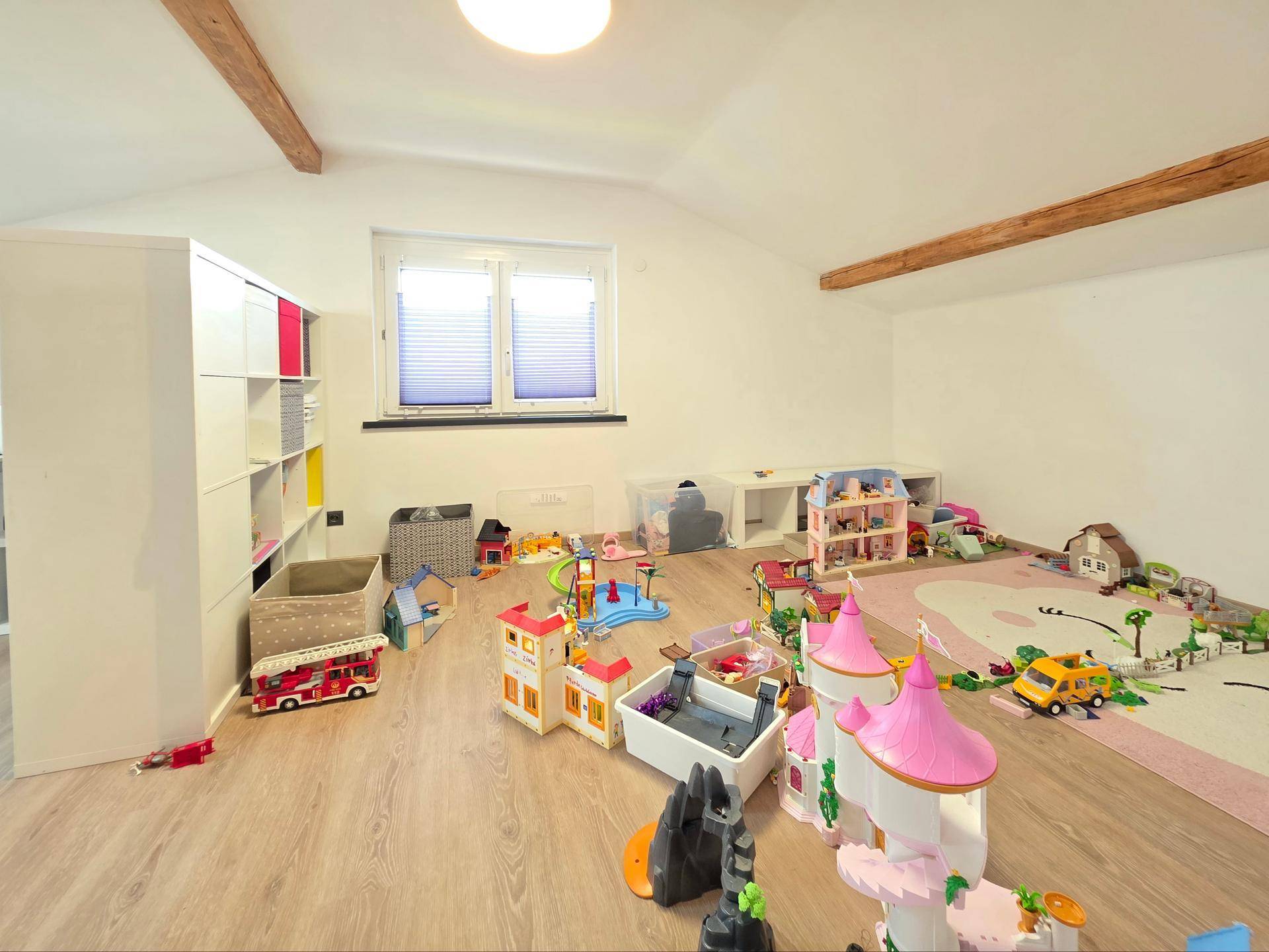 Spielbereich im Dachgeschoss mit vielen Spielsachen und einem Fenster.