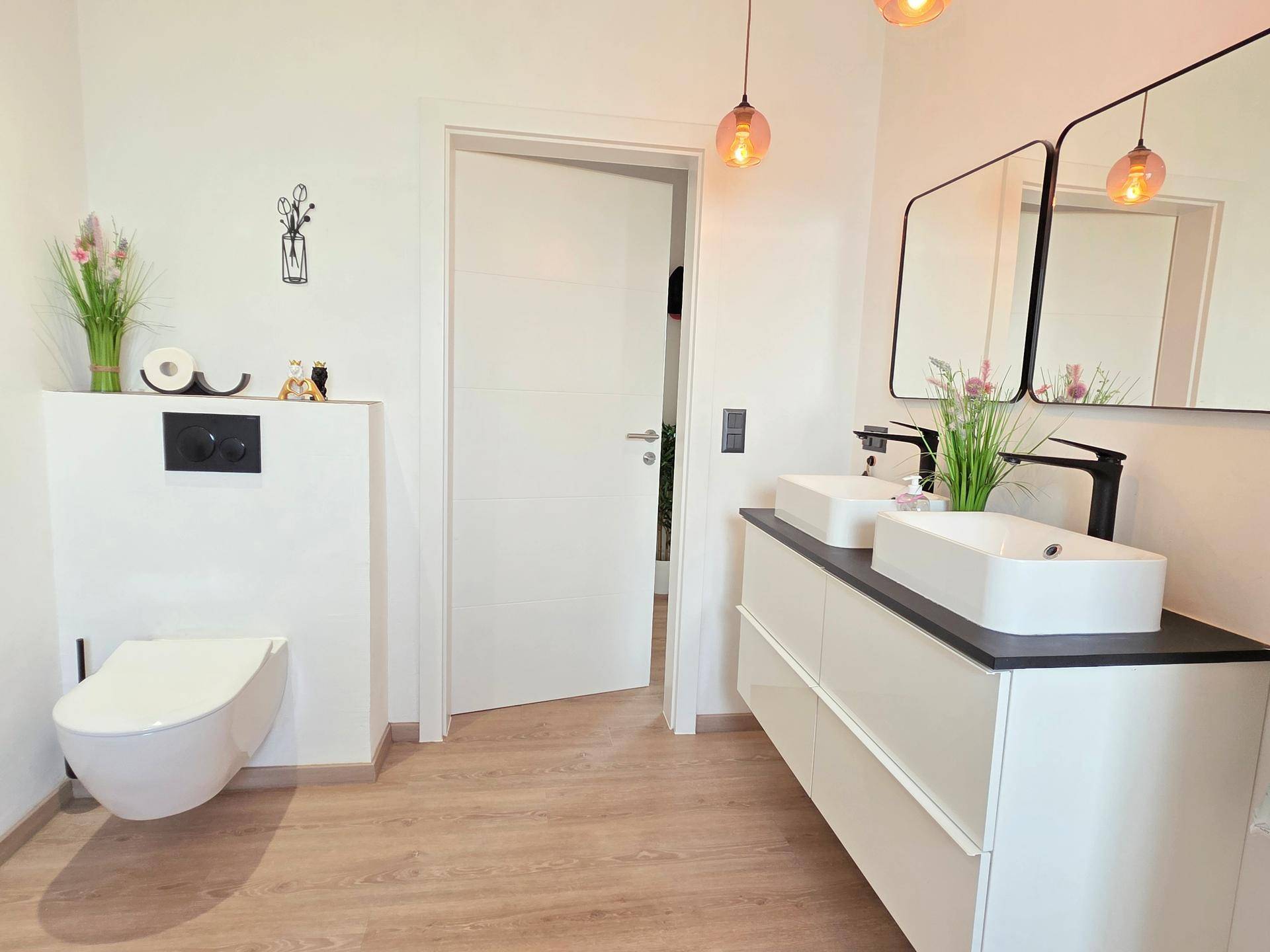 Geräumiges Badezimmer mit Doppelwaschbecken und wandhängendem WC, hell und modern gestaltet.