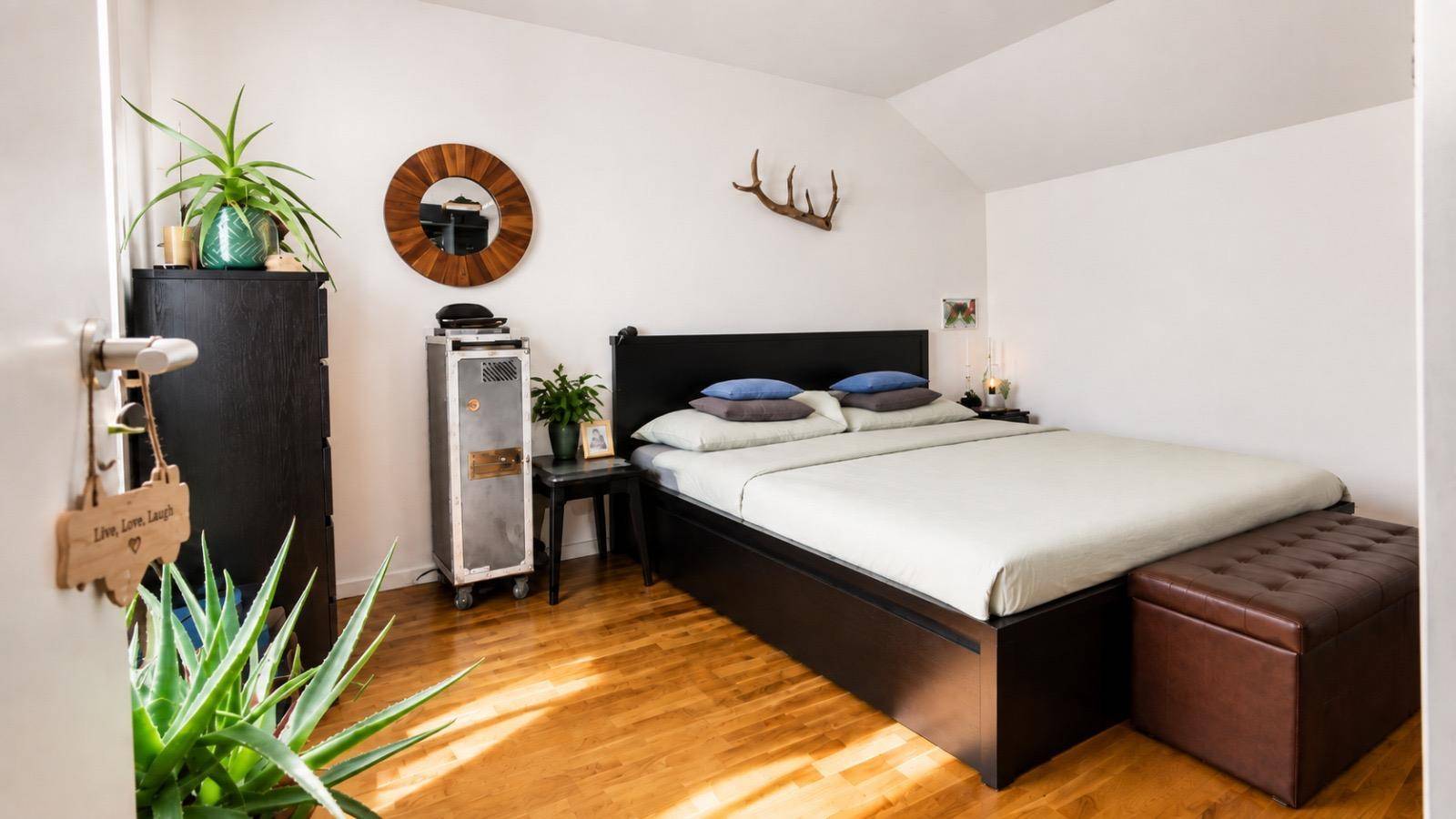 Gemütliches Schlafzimmer mit Doppelbett, Holzboden und schräger Decke.