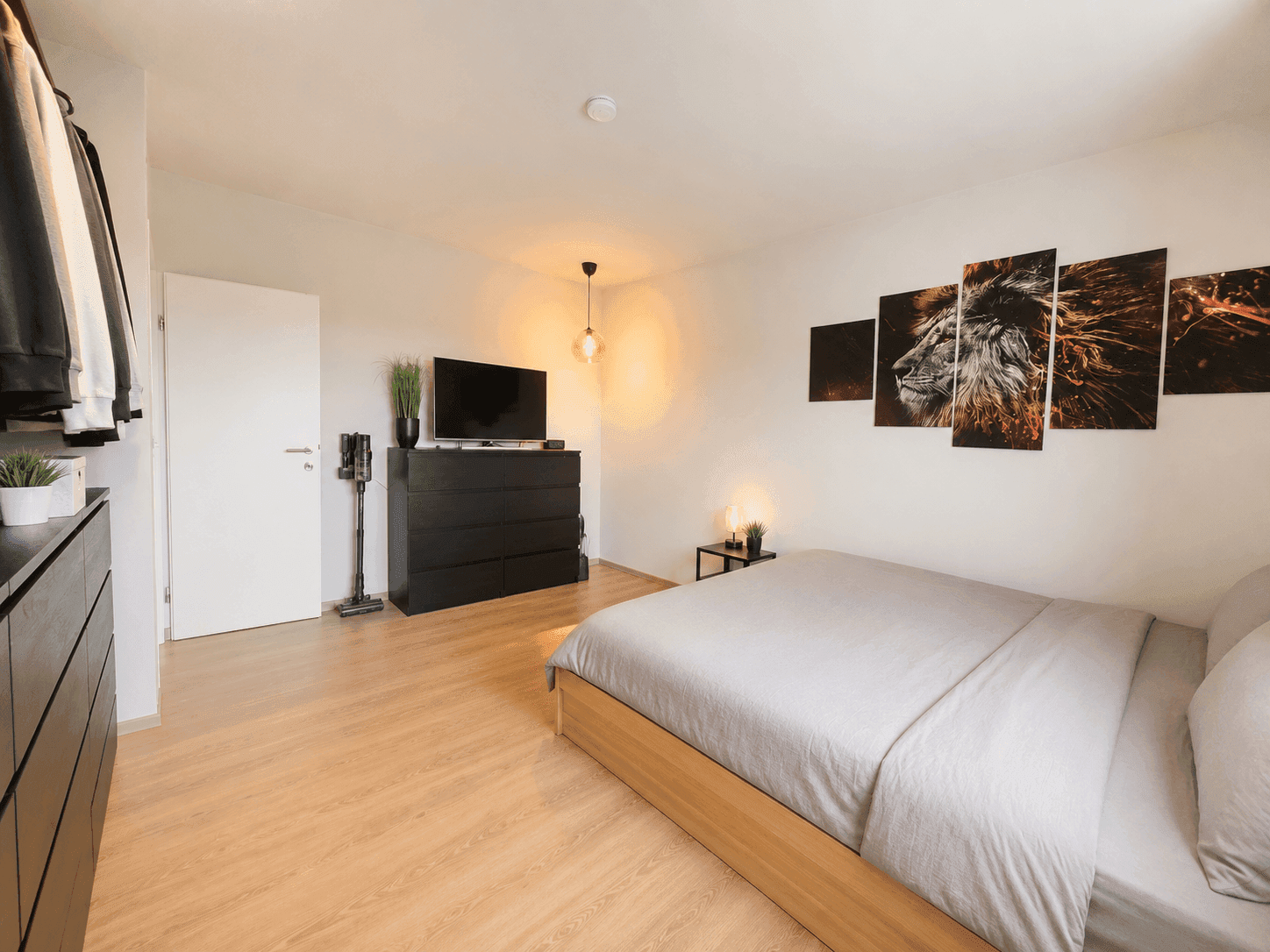 Helles Schlafzimmer mit Doppelbett, Kommode und großem Wandbild, modern eingerichtet.