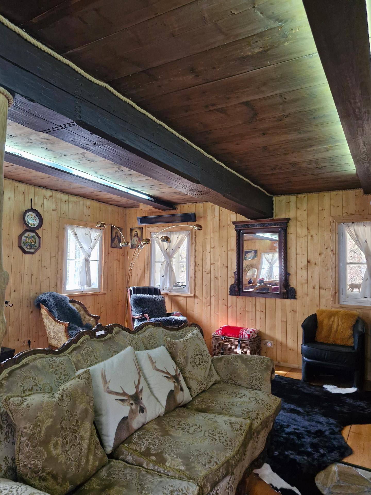 Traditionelles Wohnzimmer mit bequemen Sofas, Holzvertäfelung und dunklen Holzbalken an der Decke.