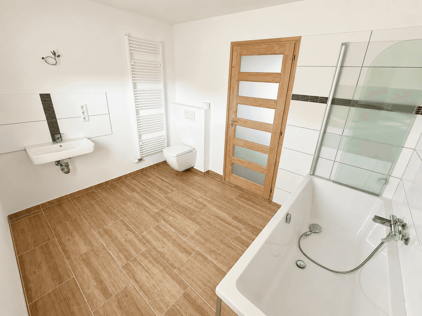 Modernes Badezimmer mit Badewanne, wandhängendem WC, Einzelwaschbecken und beheiztem Handtuchhalter.