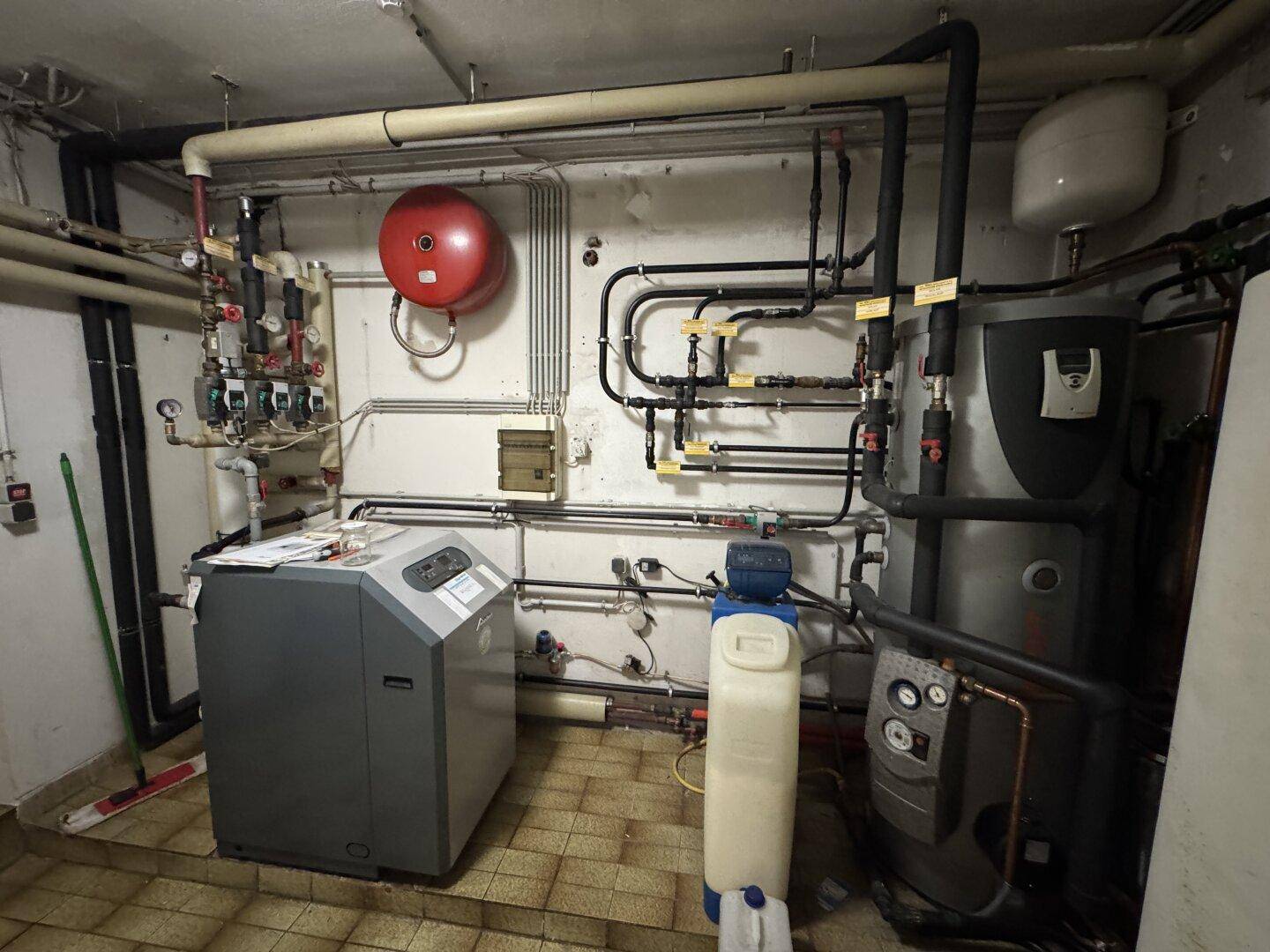 Heizungsraum im Keller mit umfangreicher Installation von Rohren und Heizkesseln.