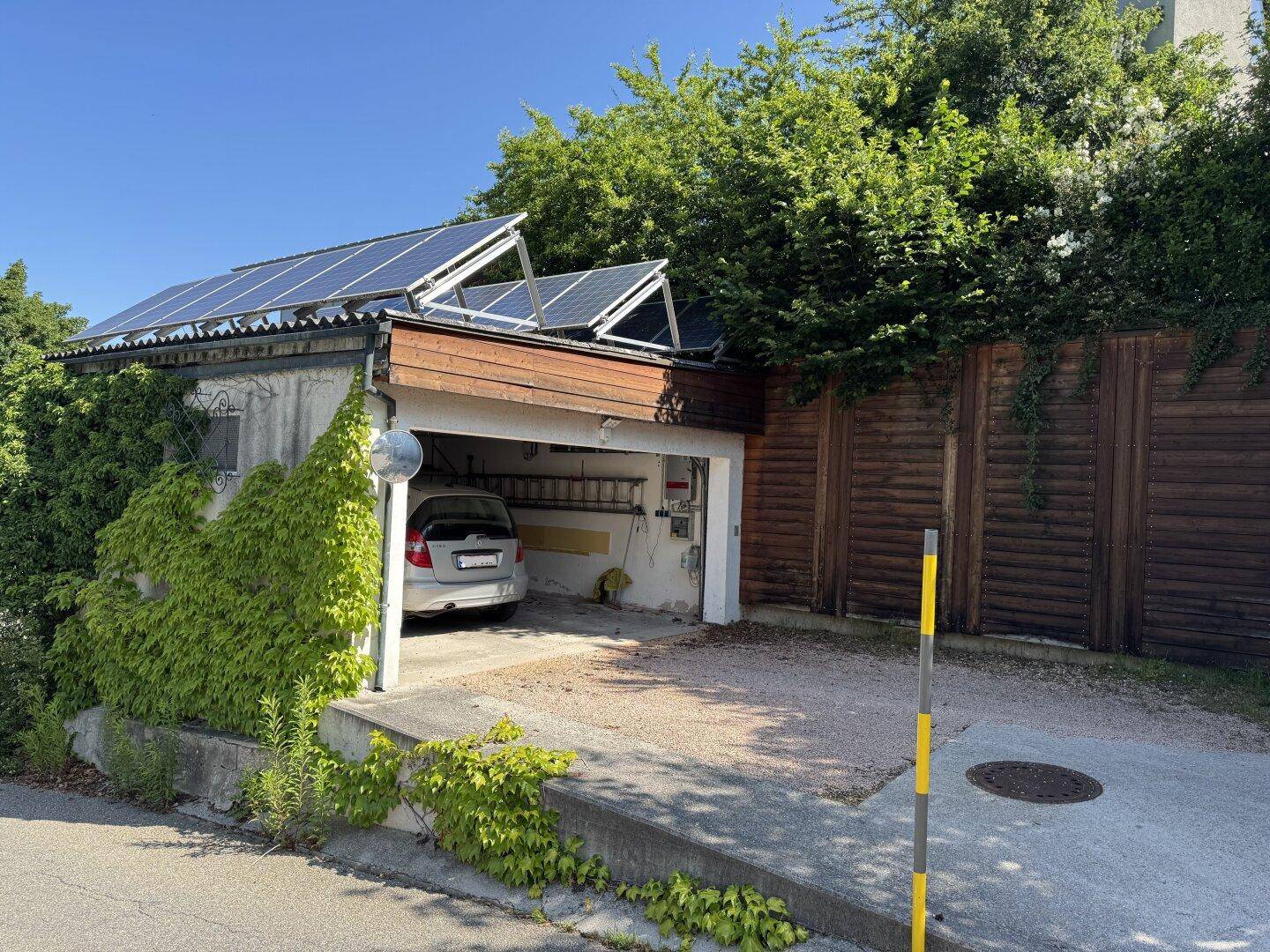 Garage mit Photovoltaikanlage auf dem Dach und Stellplatz für ein Fahrzeug.