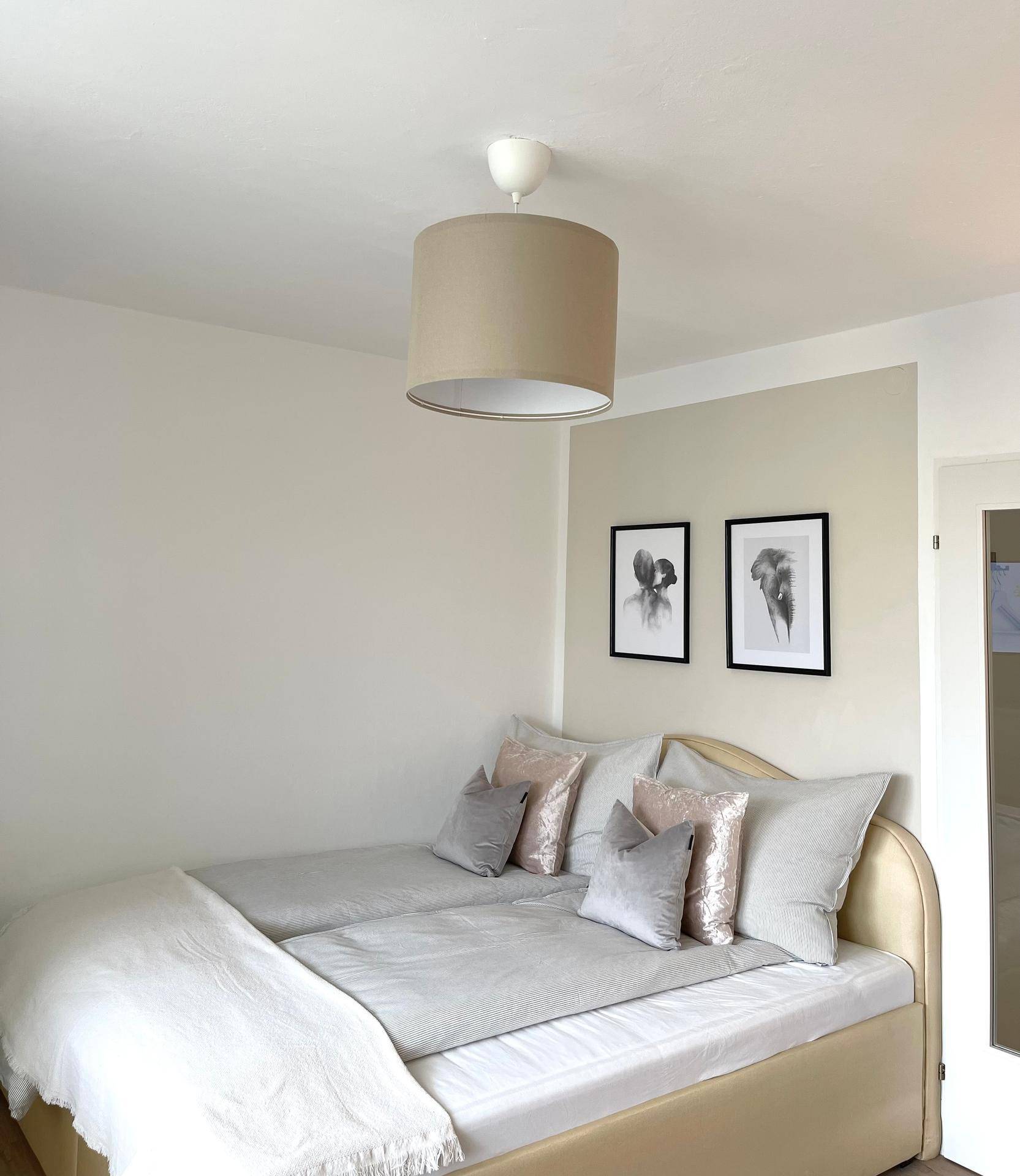 Gemütliches Schlafzimmer mit zwei Einzelbetten, schlichter Deckenleuchte und moderner Wanddekoration.