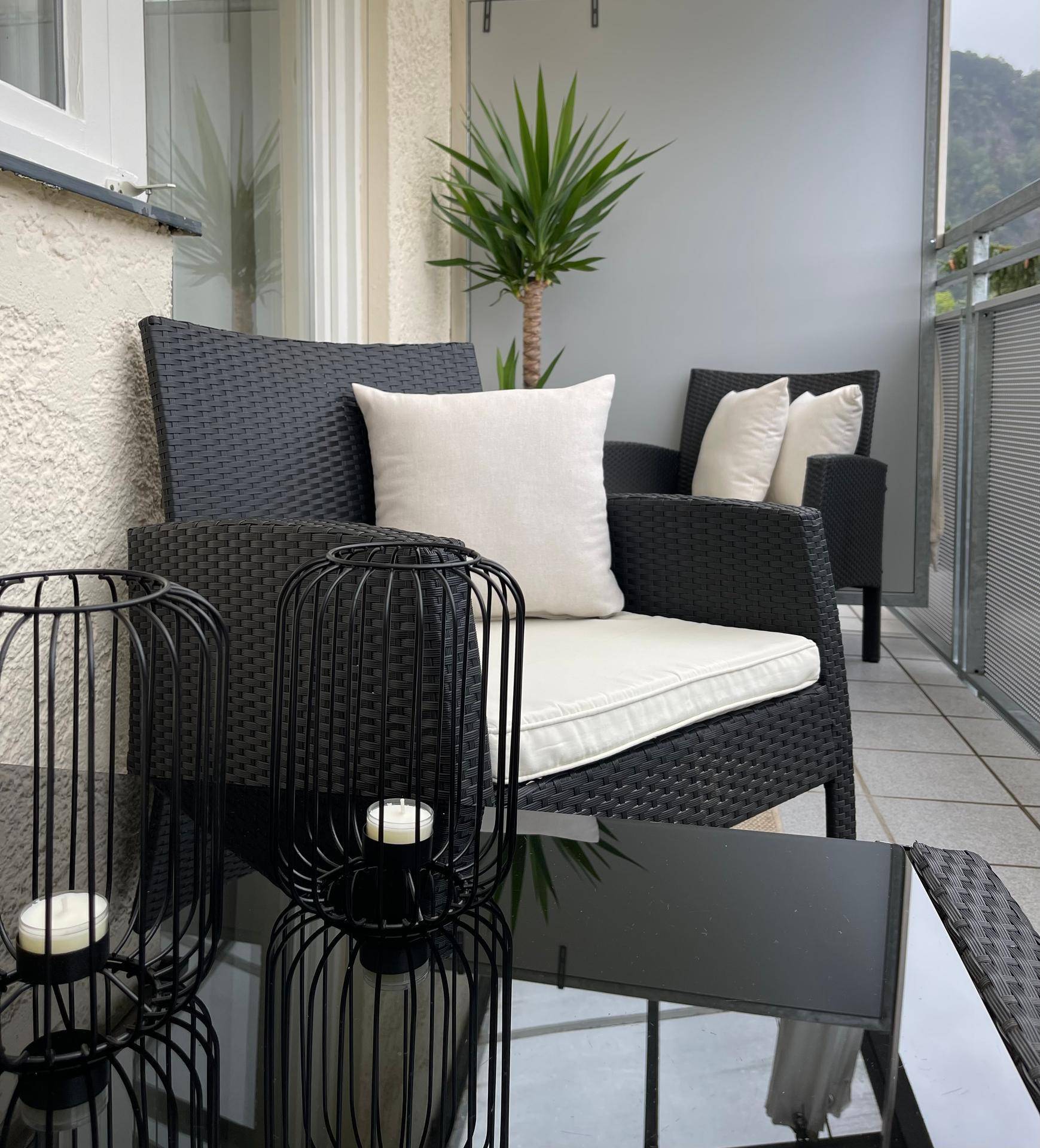 Gemütlicher Balkon mit Korbsesseln, Beistelltisch und einer Palme für entspannte Stunden.