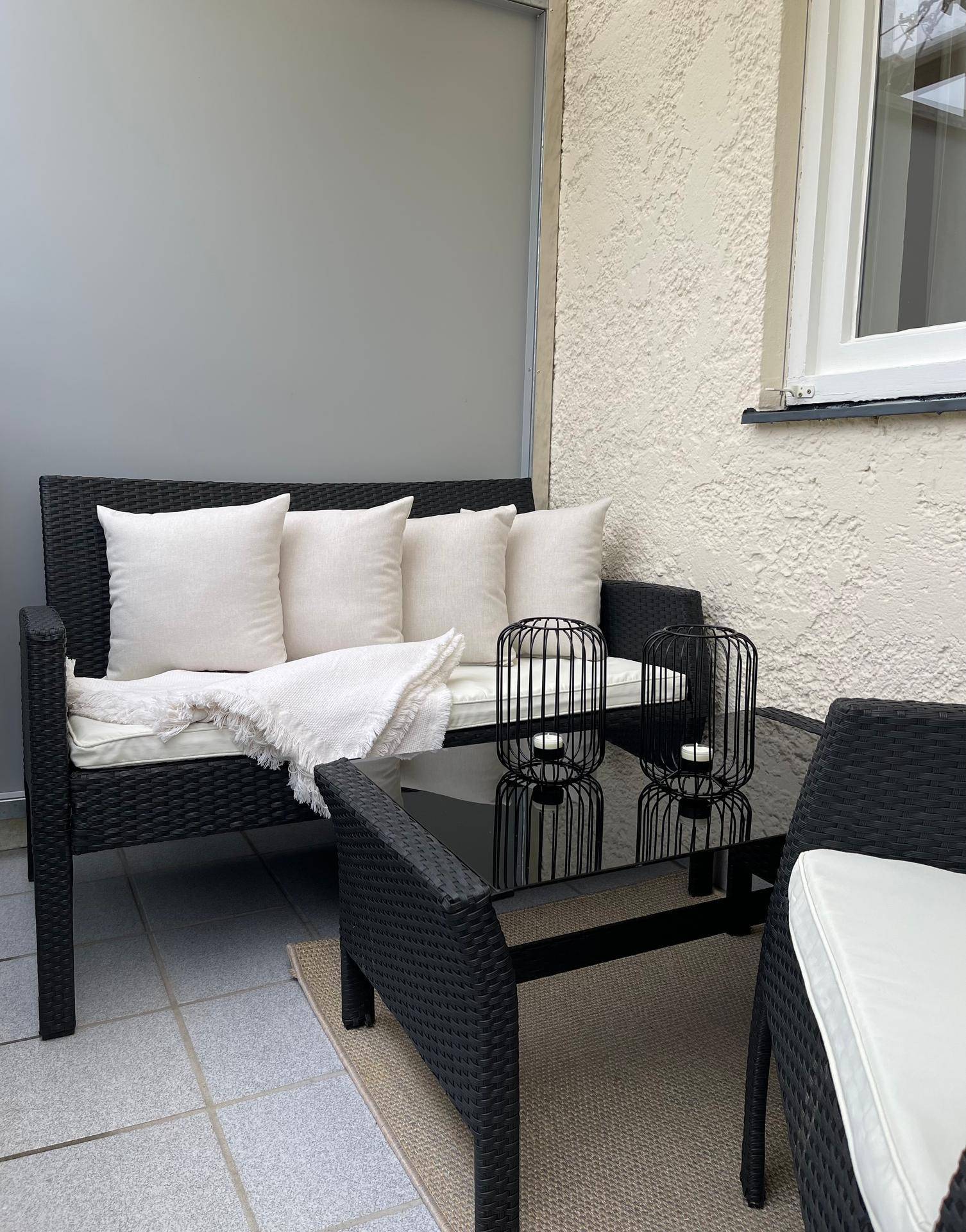 Balkon mit bequemer Sitzgruppe, Couchtisch und einem Teppich für eine wohnliche Atmosphäre im Freien.