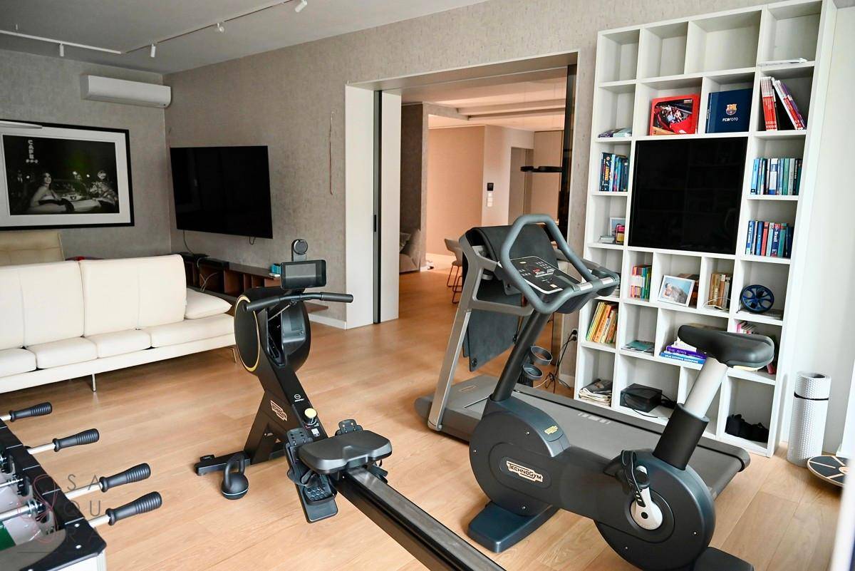 Geräumiger Wohnbereich mit Fitnessgeräten, einem Kicker und einem weißen Sofa.