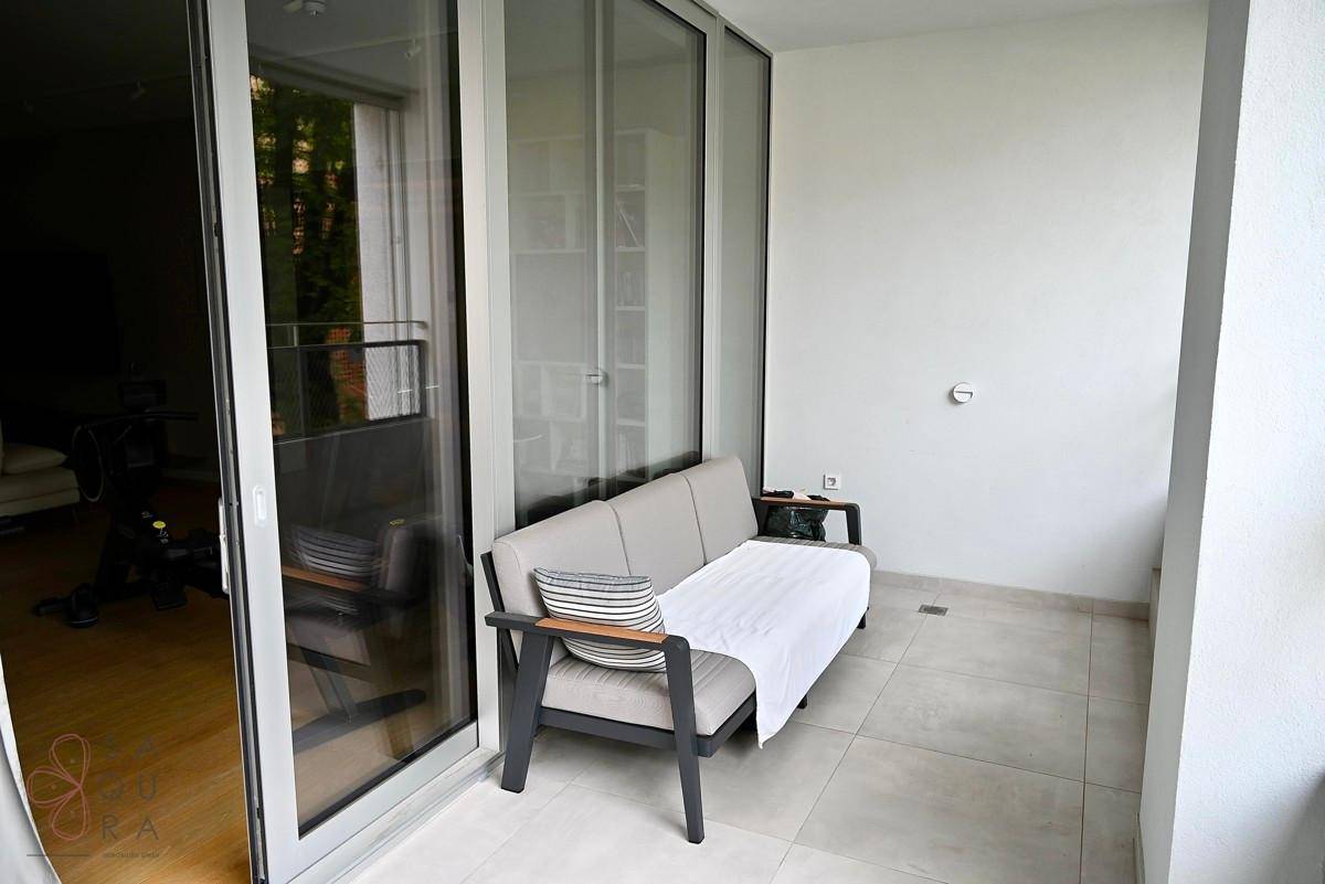Kleiner Balkon mit bequemer Outdoor-Sitzgelegenheit und Fliesenboden, ideal zum Entspannen.