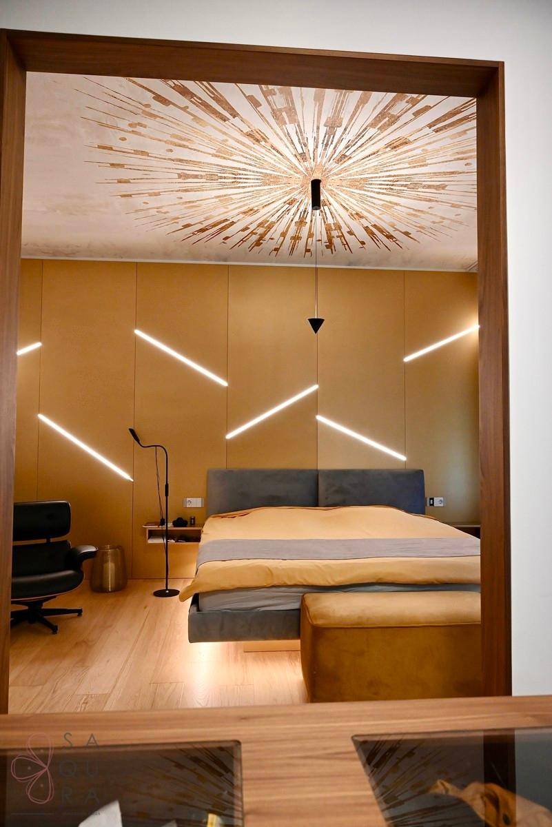 Schlafzimmer mit auffälliger Deckenbeleuchtung und modernem Interieur, durch einen Türrahmen gesehen.