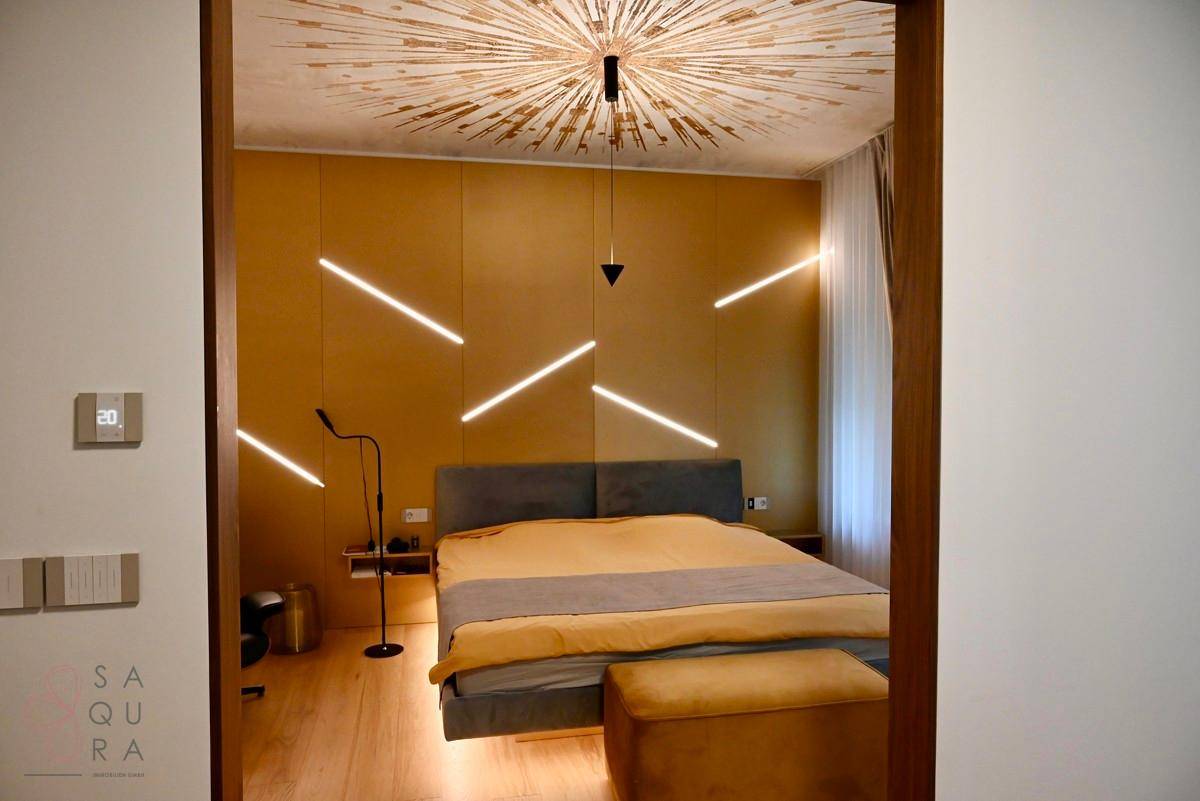 Modernes Schlafzimmer mit einzigartiger Deckenbeleuchtung, bequemen Bett und dekorativen Wandleuchten.