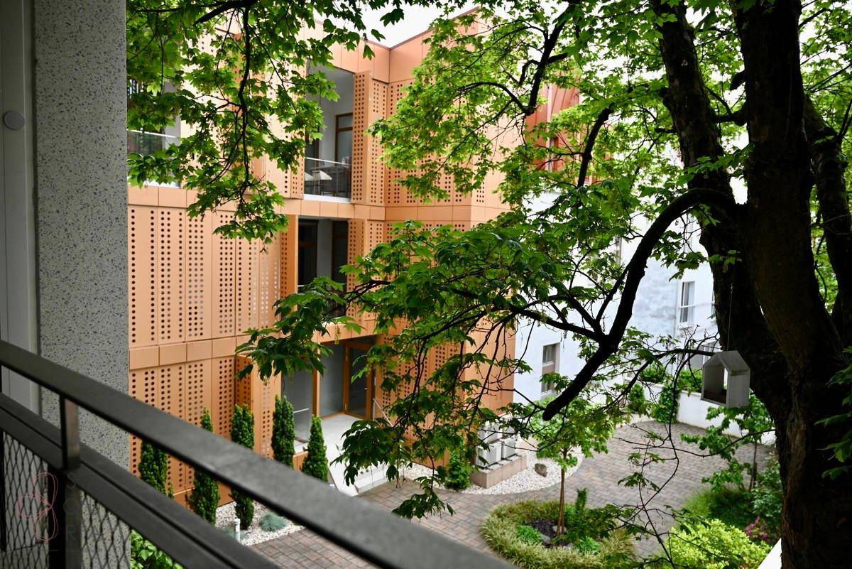 Blick auf einen begrünten Innenhof mit moderner Gebäudefassade und gepflegten Pflanzen.