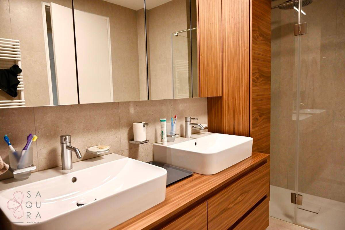 Geräumiges Badezimmer mit doppelten Waschbecken auf Holzunterschrank und großem Spiegelschrank.
