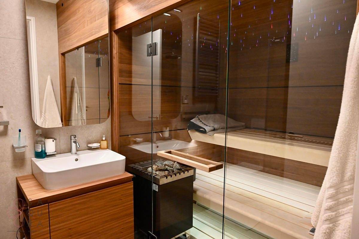 Elegantes Badezimmer mit Sauna, modernem Waschbecken und stilvoller Holzvertäfelung.