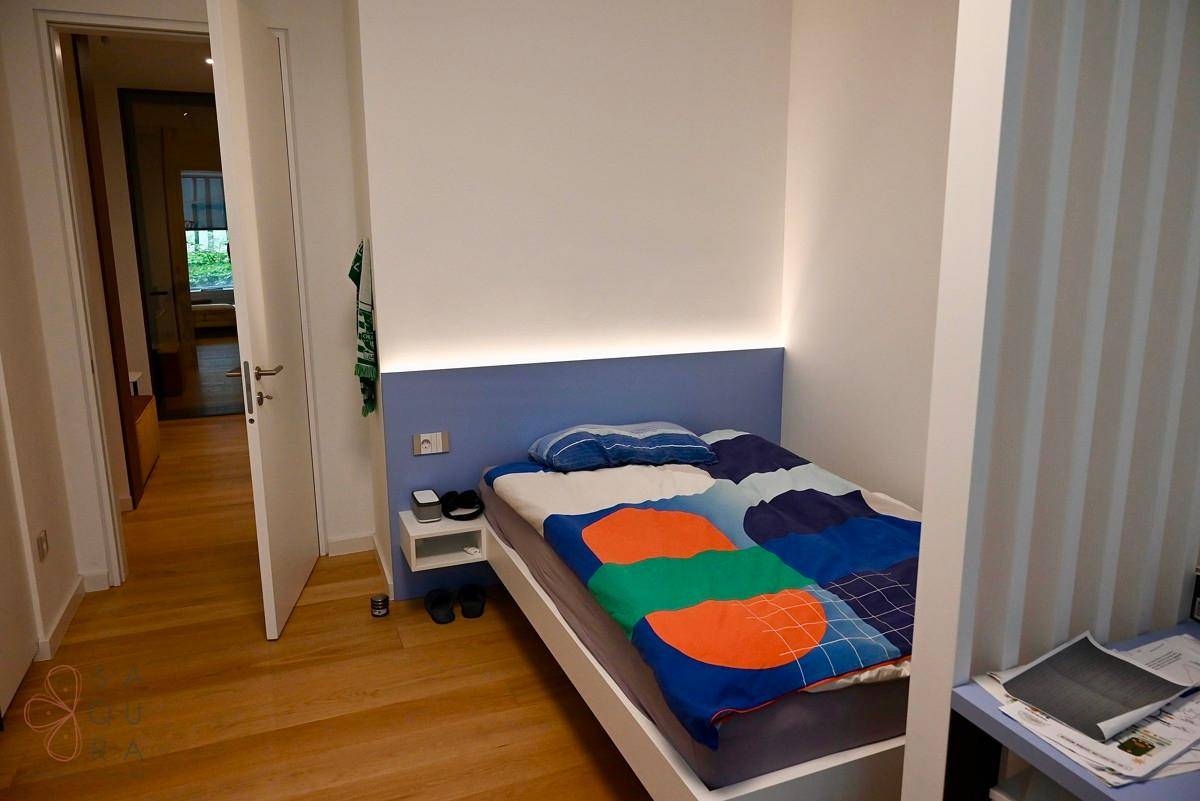 Gemütliches Schlafzimmer mit Einzelbett, integrierter Beleuchtung und Holzboden.