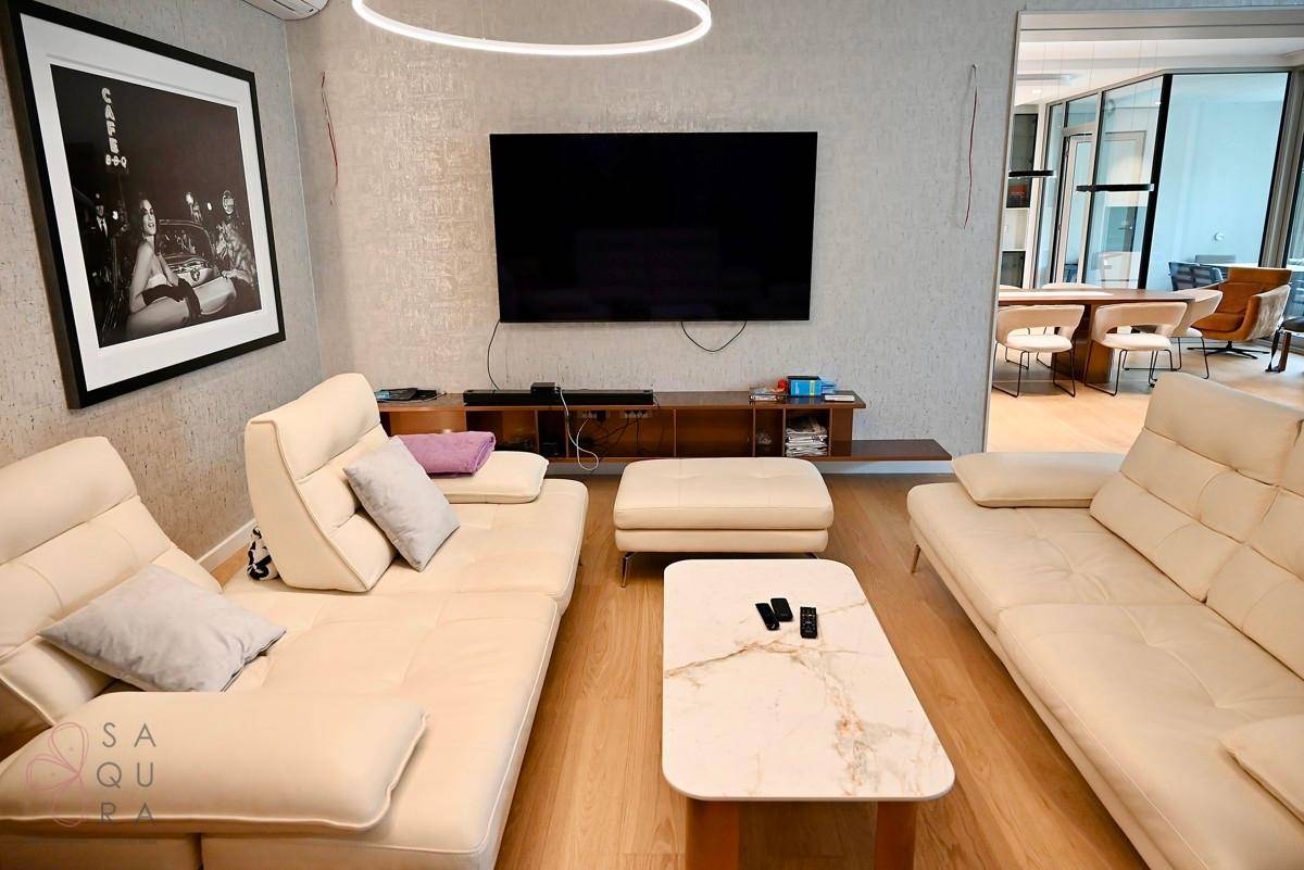 Gemütliches Wohnzimmer mit bequemen Sofas, großem Fernseher und Blick auf den Essbereich.