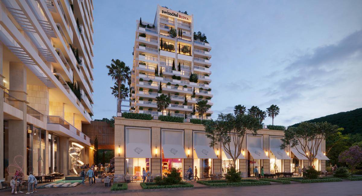 Moderne Architektur mit Geschäften und Cafés im Erdgeschoss, beleuchtet in der Abenddämmerung.
