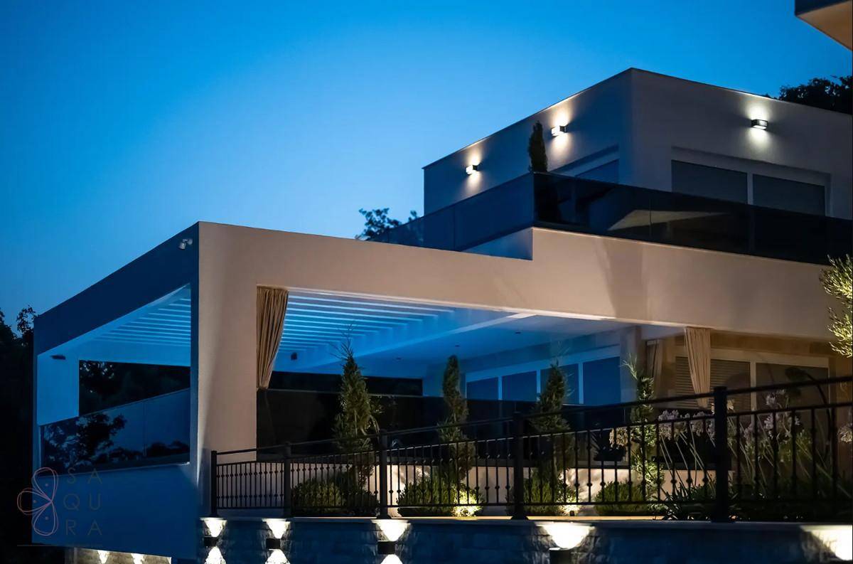 Die moderne Villa bei Nacht, beleuchtet mit stimmungsvoller Außenbeleuchtung und klarem Nachthimmel.