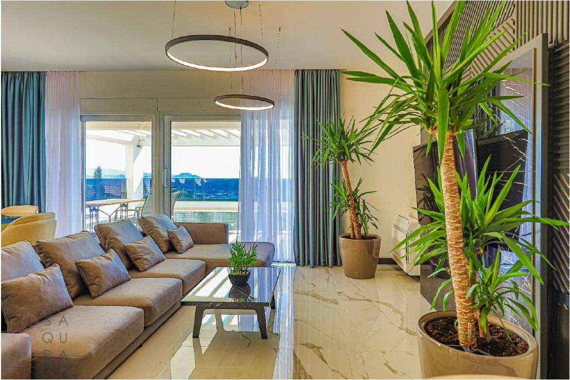 Geräumiges Wohnzimmer mit bequemer Couch, modernen Pflanzen und hellem Fliesenboden.