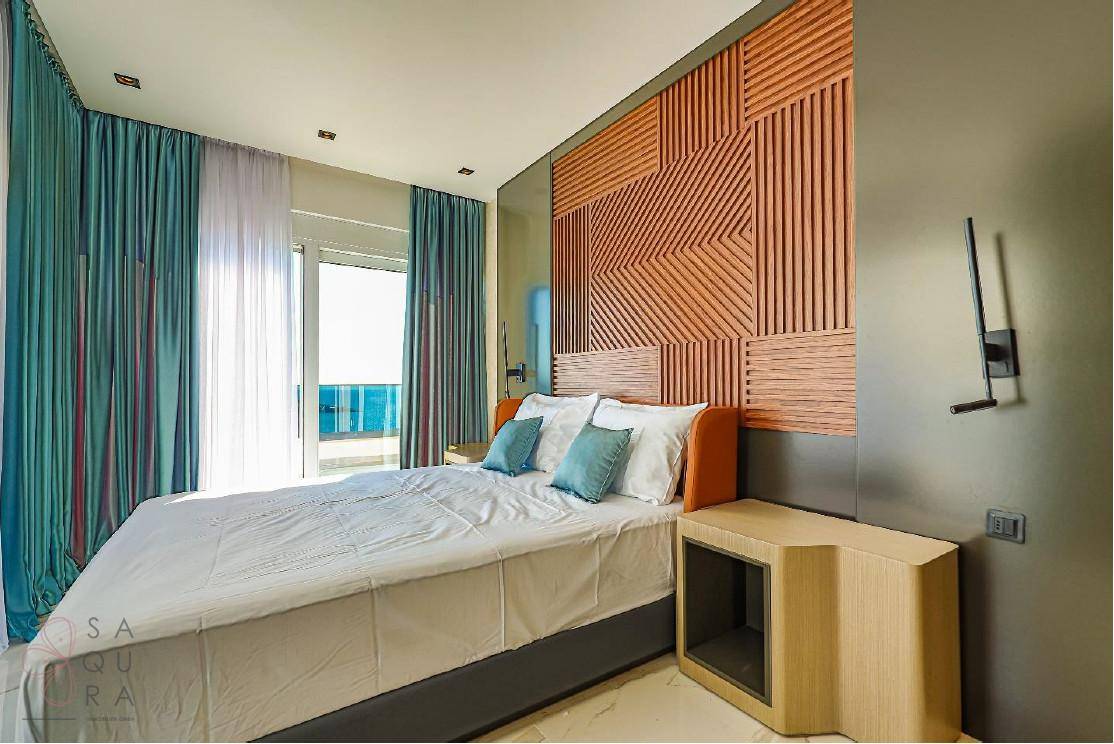 Modernes Schlafzimmer mit Doppelbett, Holzwandpaneelen und Zugang zu einem Außenbereich.